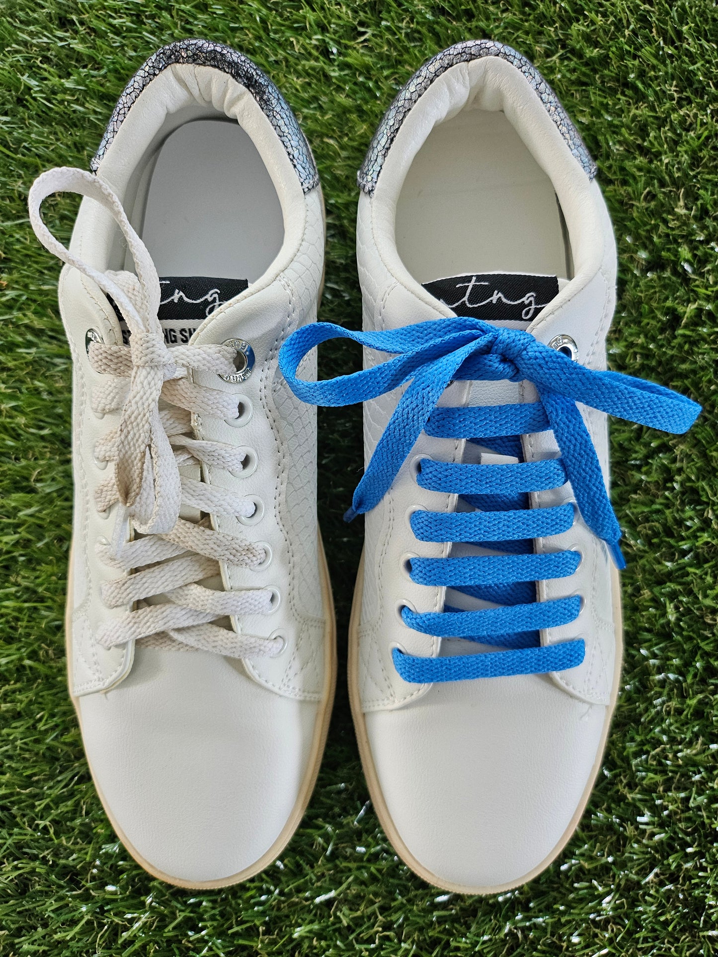 White sneakers with blue laces on a grass background