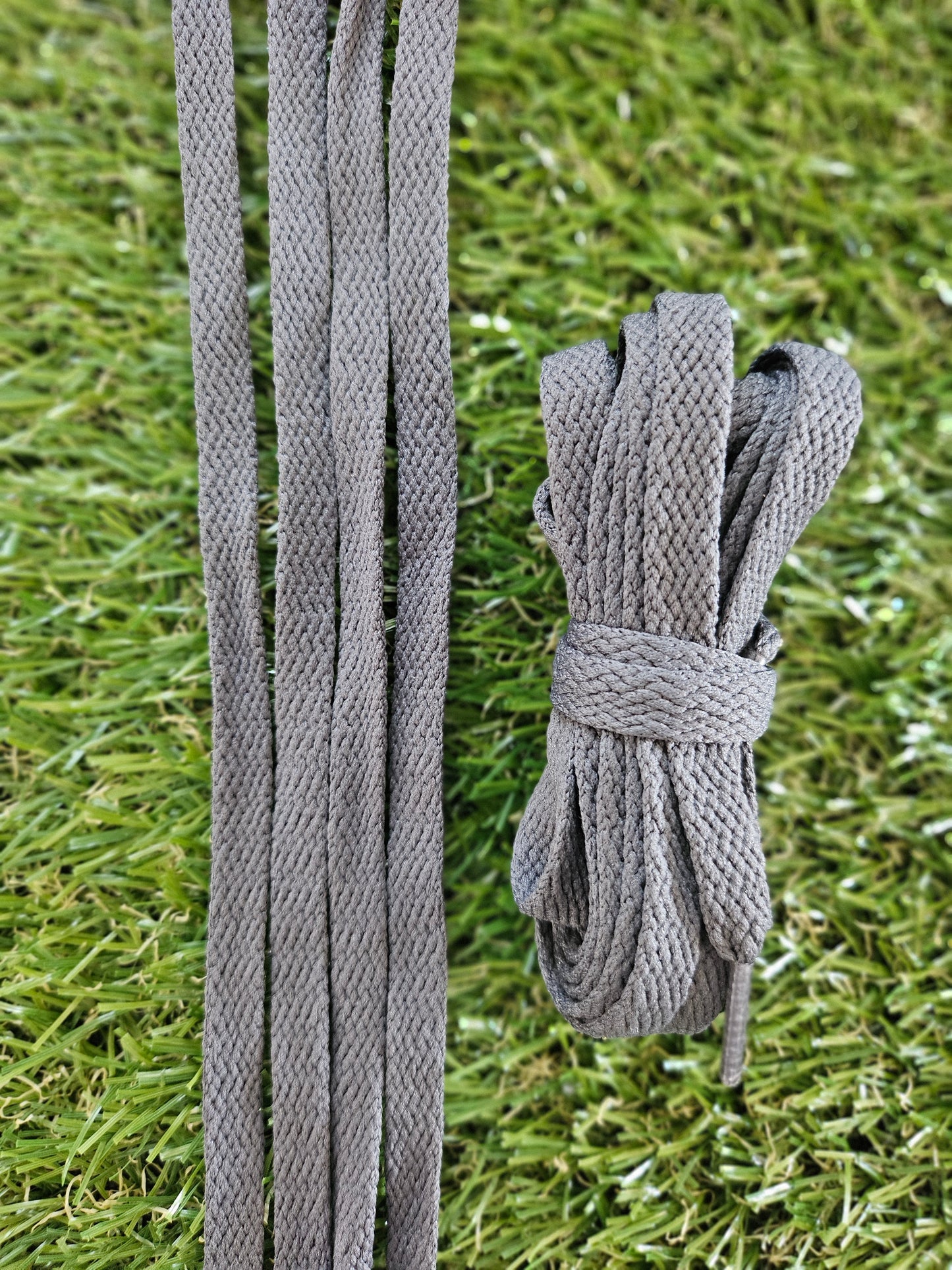 Dark grey shoelaces on green grass