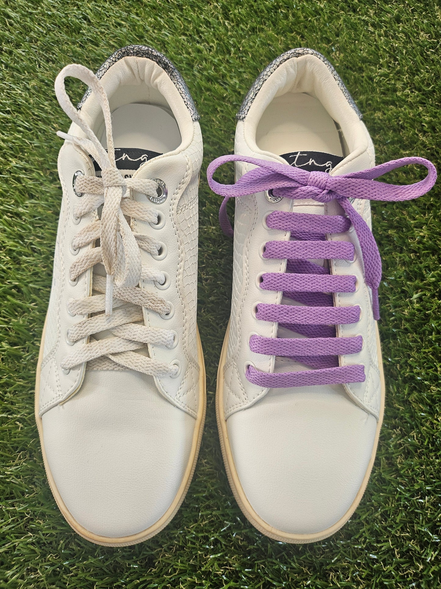 White sneakers with purple laces on grass