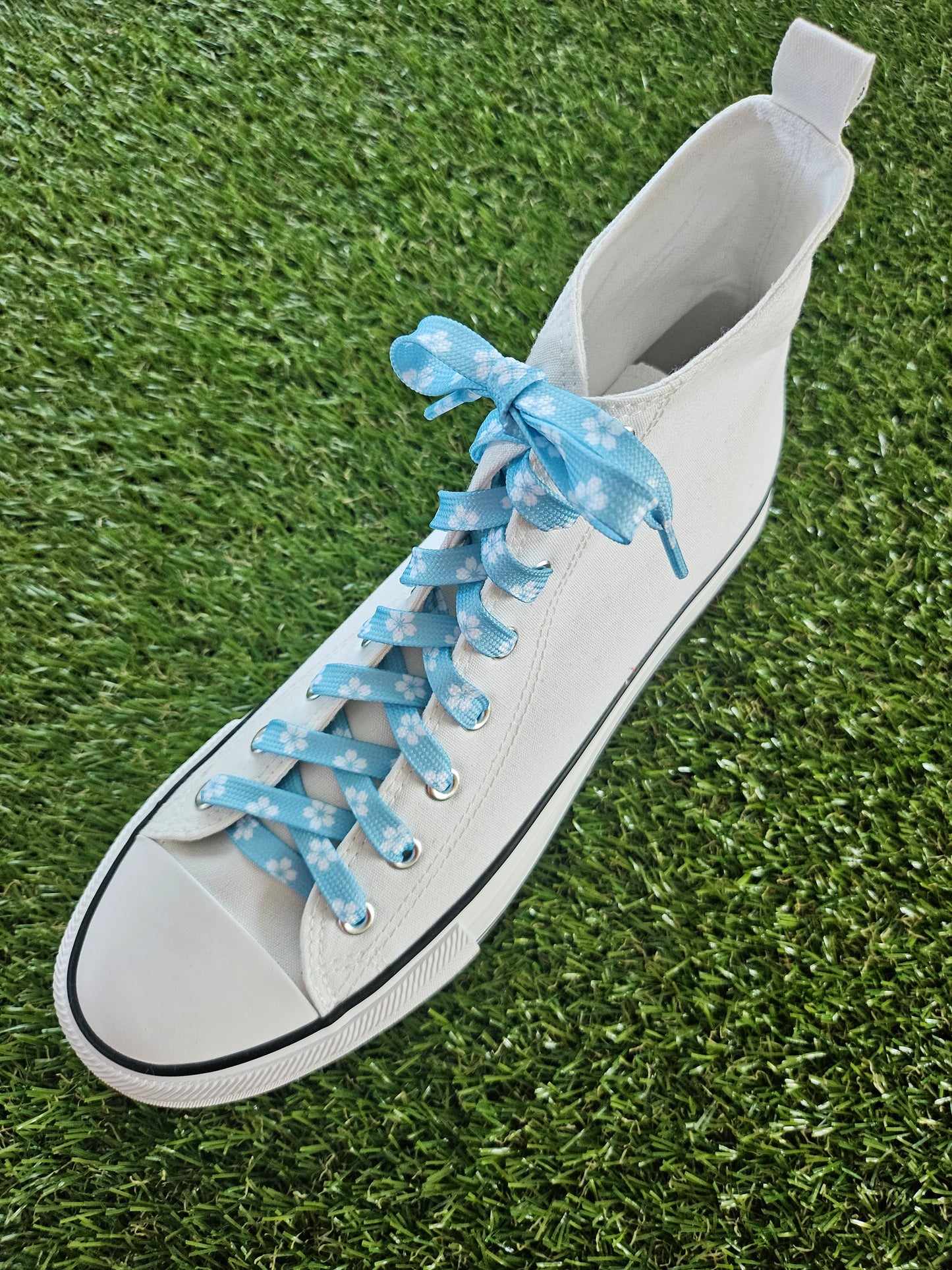 White sneaker with blue laces on a grass background