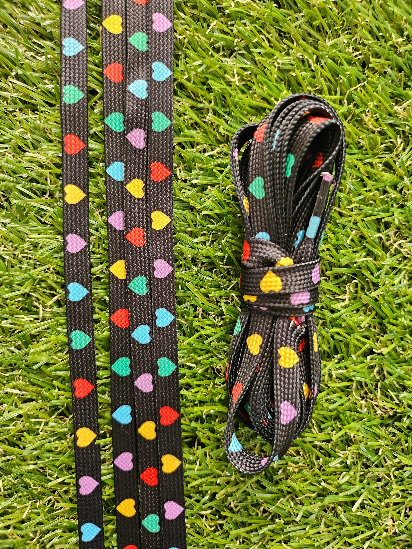 Black & Multi Coloured Heart Laces lying on the grass