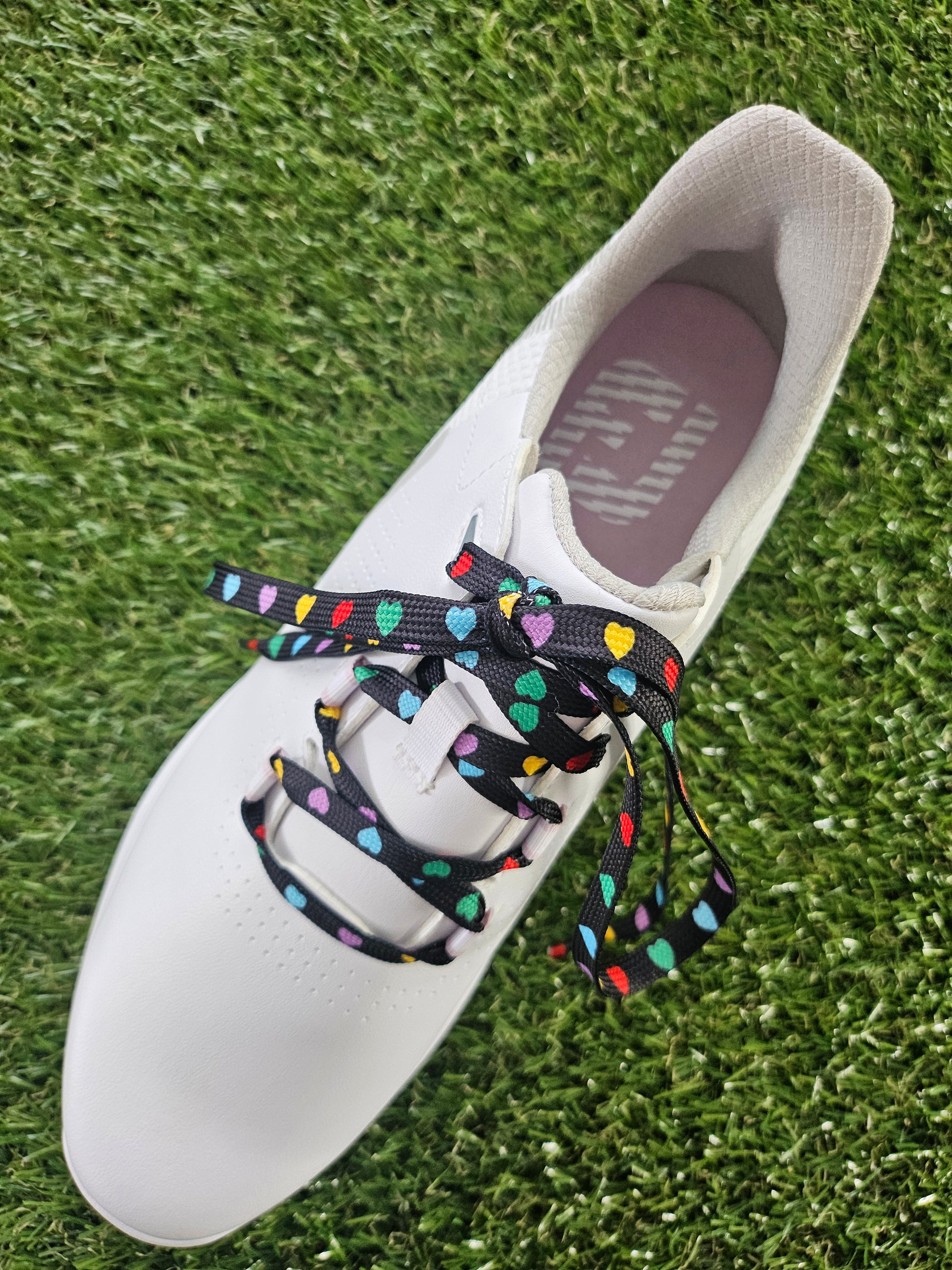 white golf shoe with black laces with multi coloured heart pattern