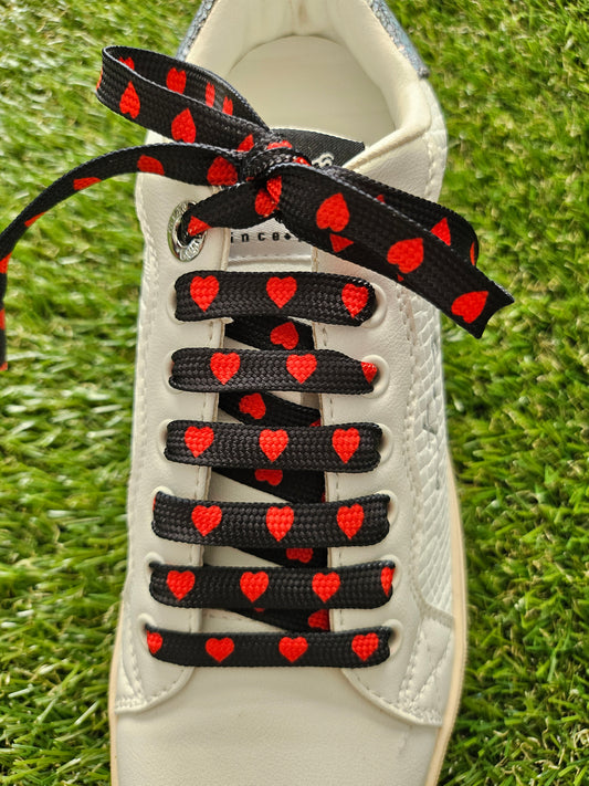 Black shoelaces with red hearts on grass
