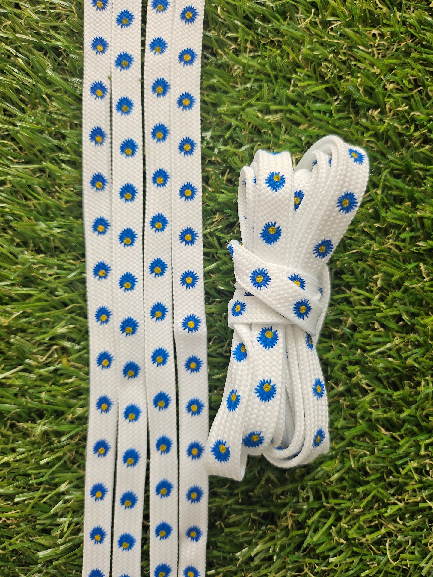 White shoelaces with blue floral patterns on a grass background