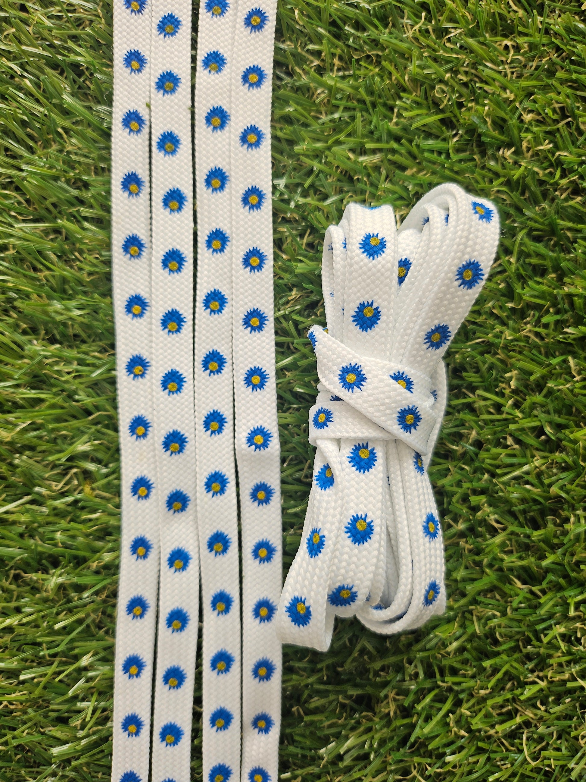 White shoelaces with blue floral patterns on a grass background