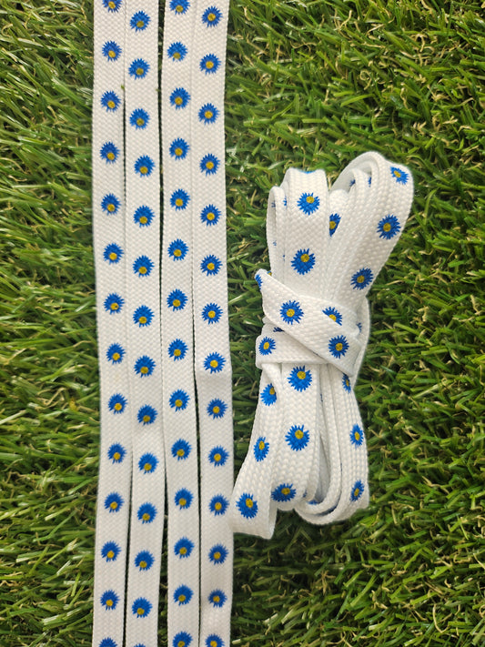 White shoelaces with blue floral patterns on a grass background