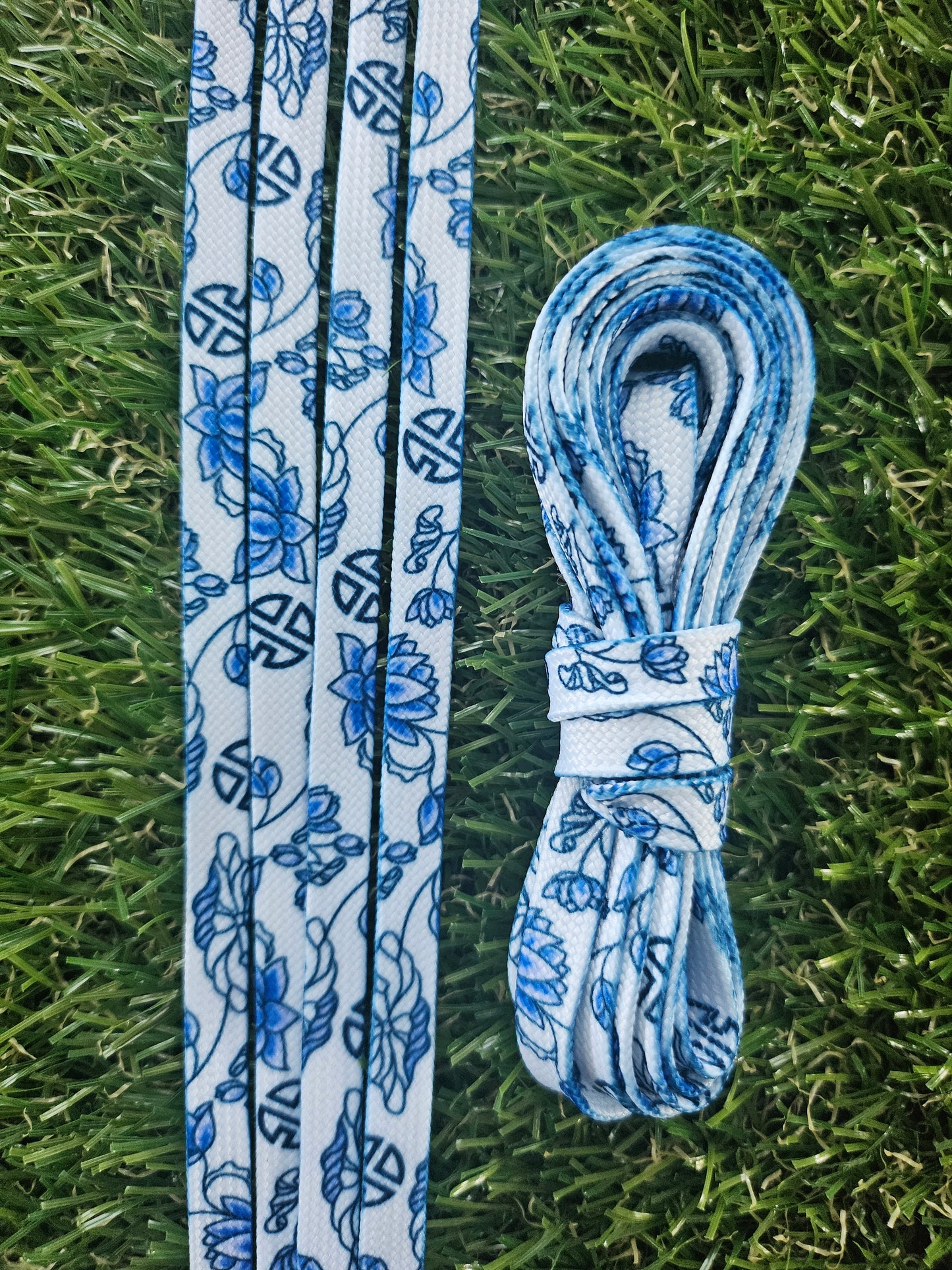 Blue and white floral-patterned shoelaces on grass
