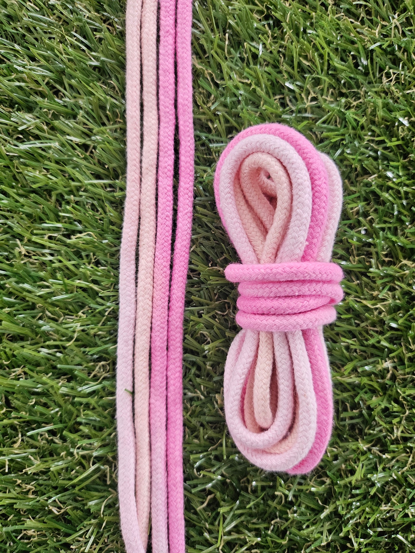 Pink shoelaces tied in a knot on green grass