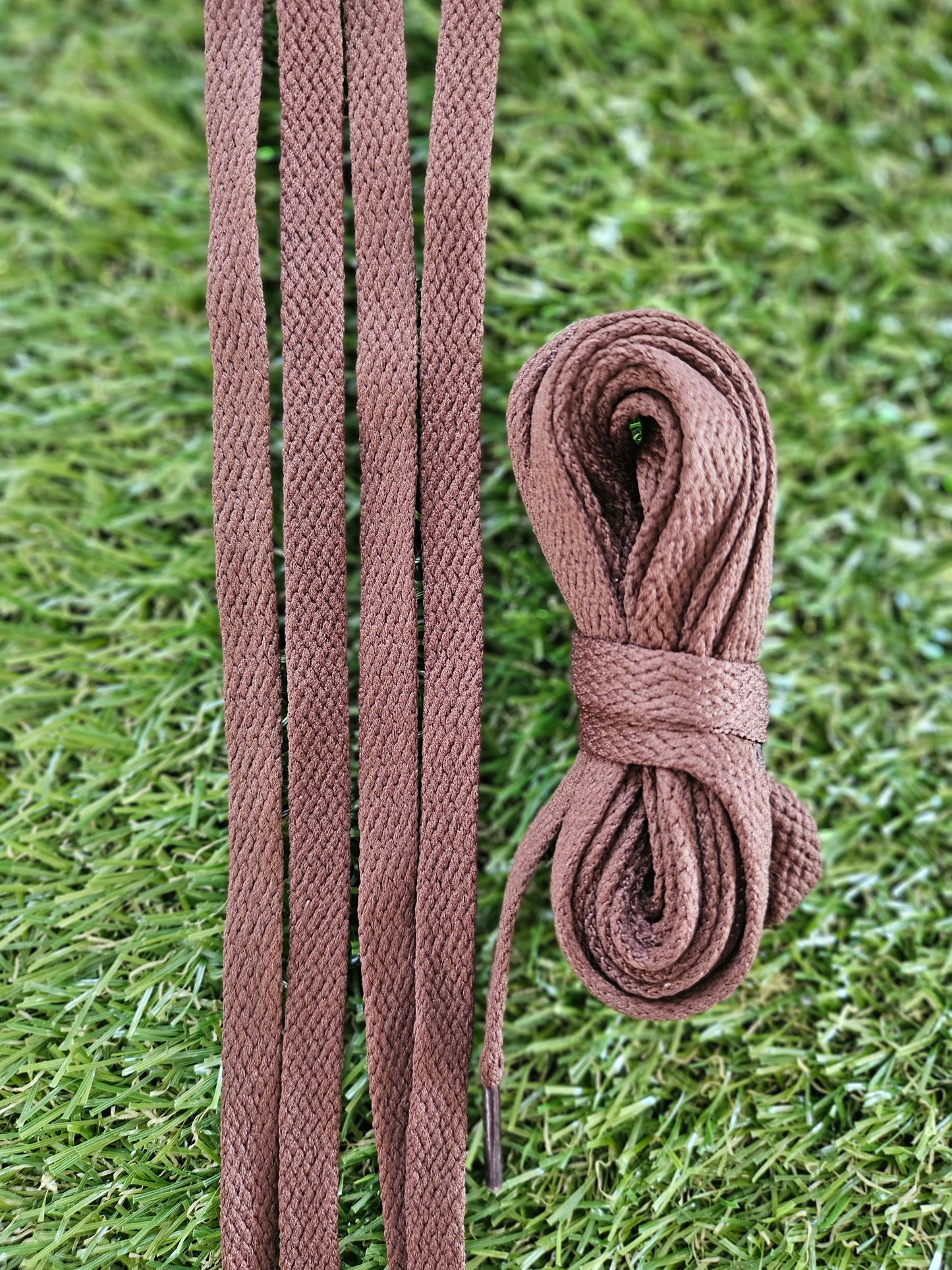 Brown braided shoelaces on a grass background