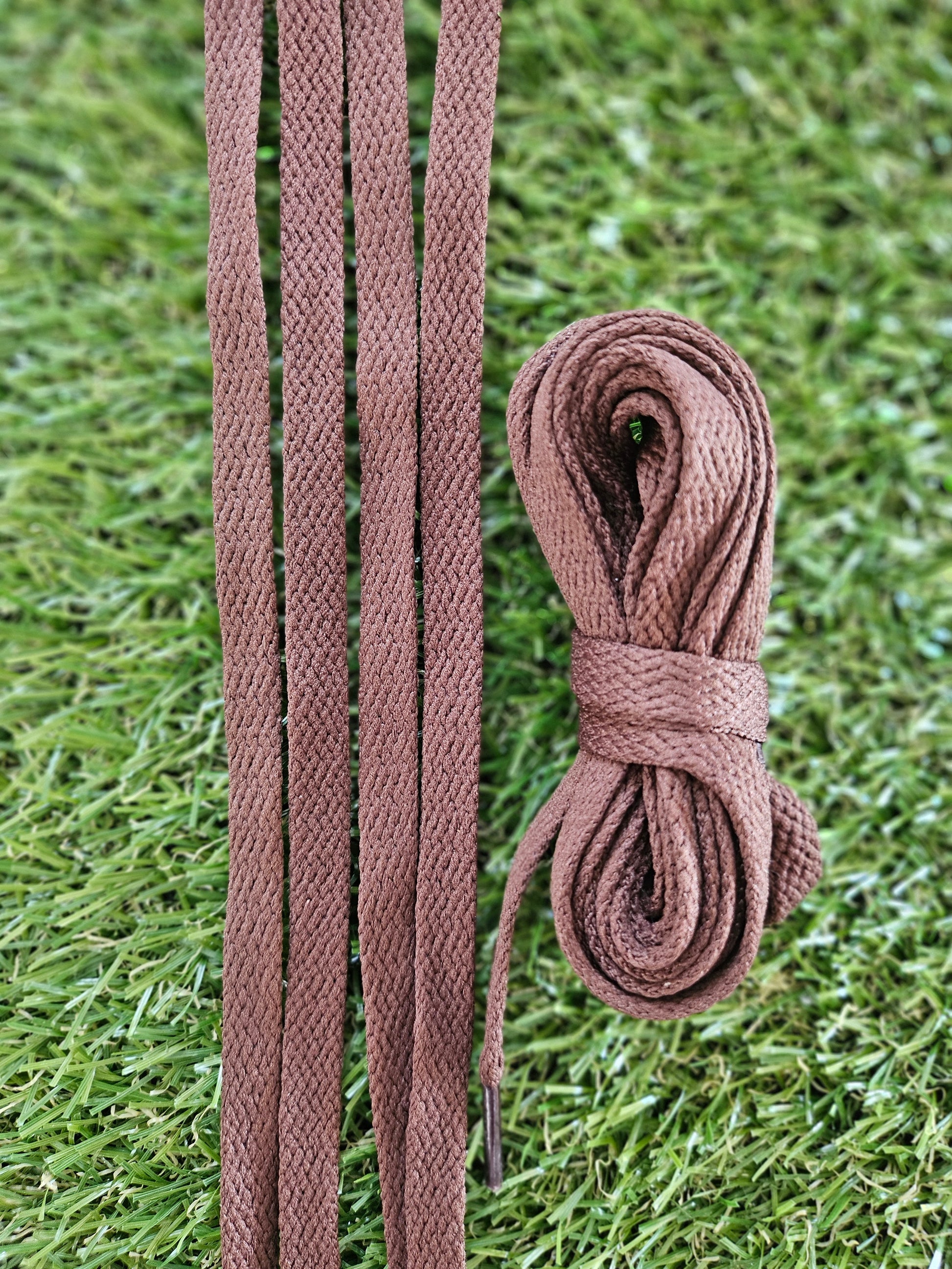 Brown braided shoelaces on a grass background