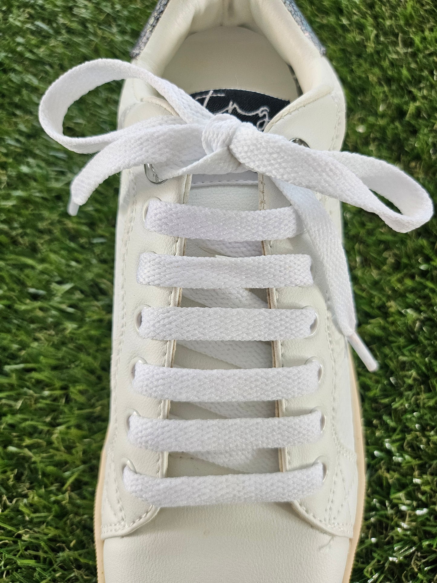 White shoelaces on a white sneaker on grass