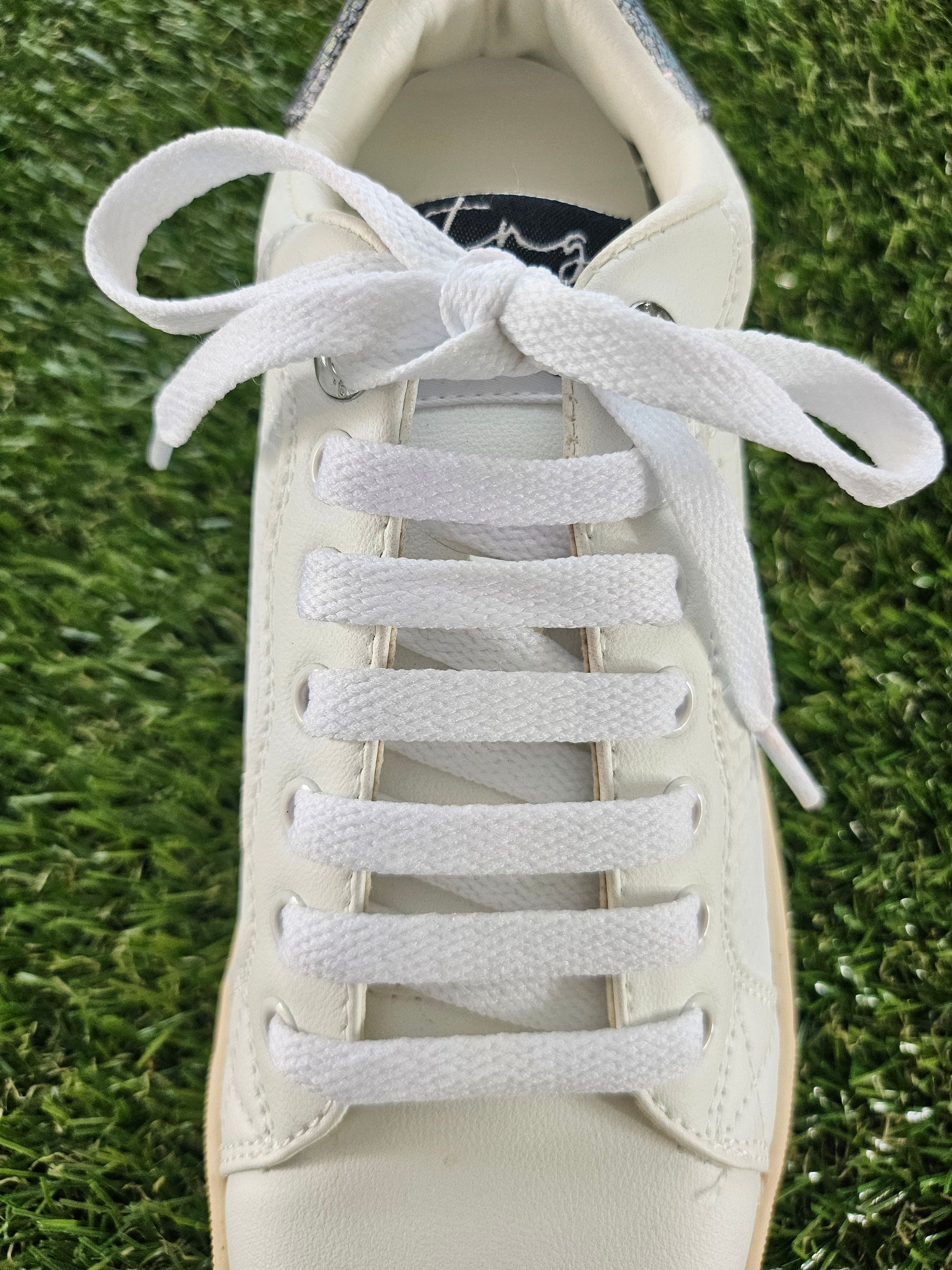 White shoelaces on a white sneaker on grass