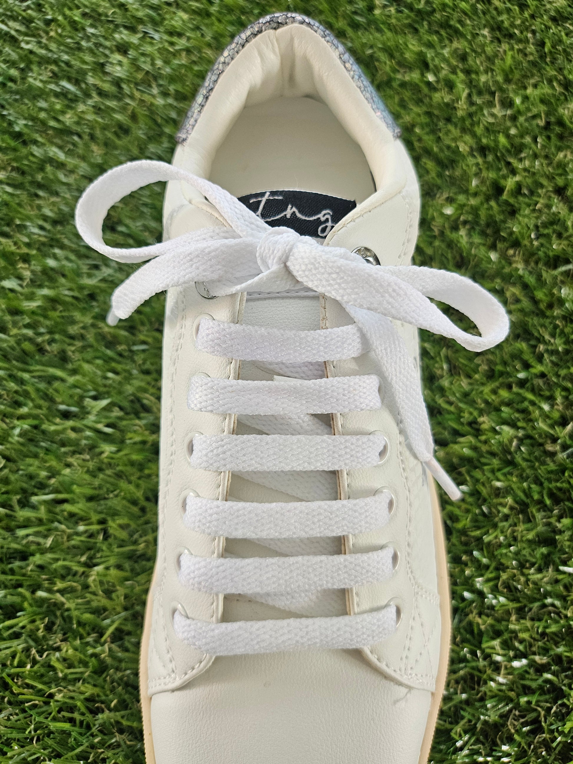 White sneaker with laces on a grass background