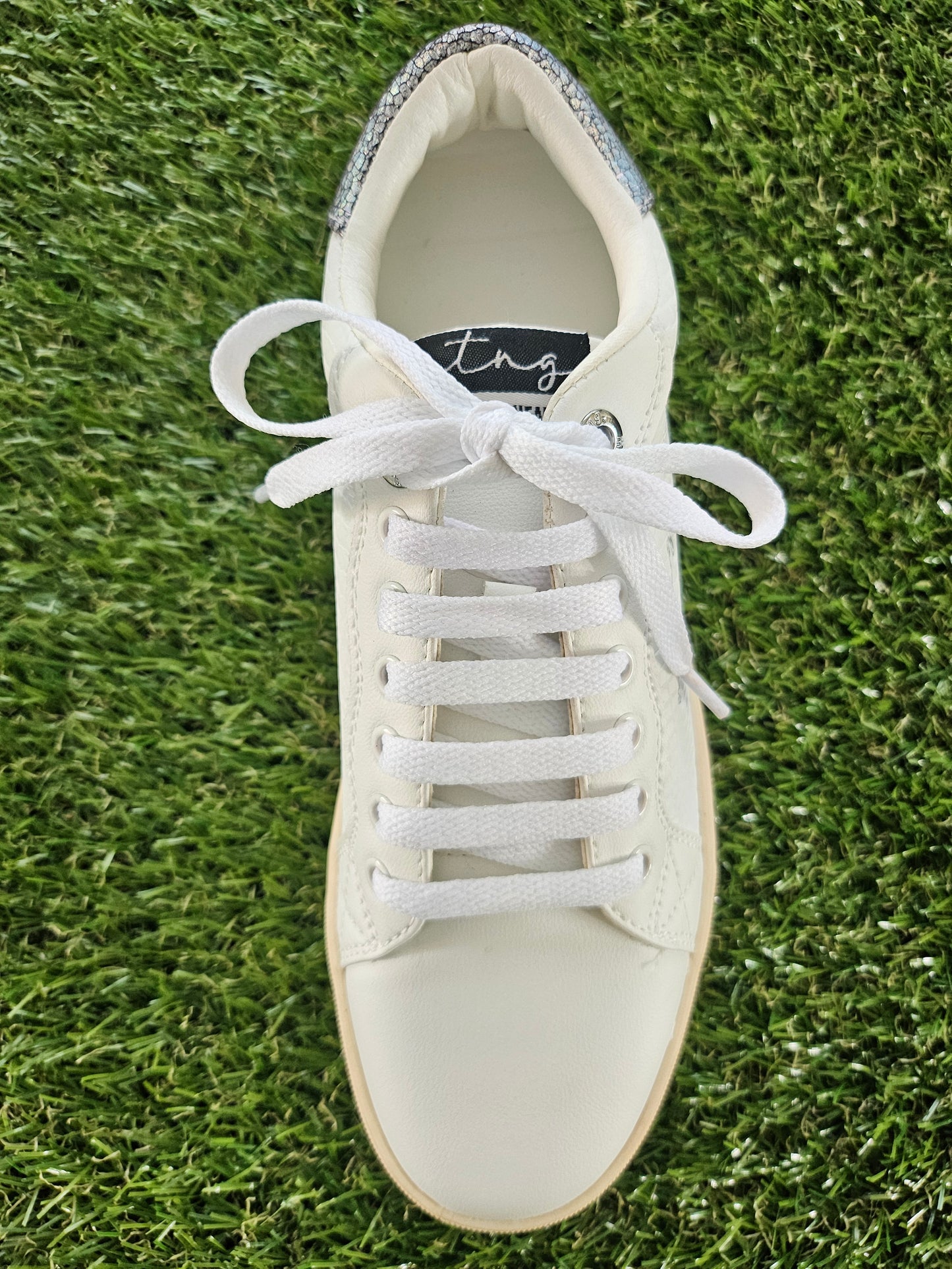 White sneaker with laces on a grass background