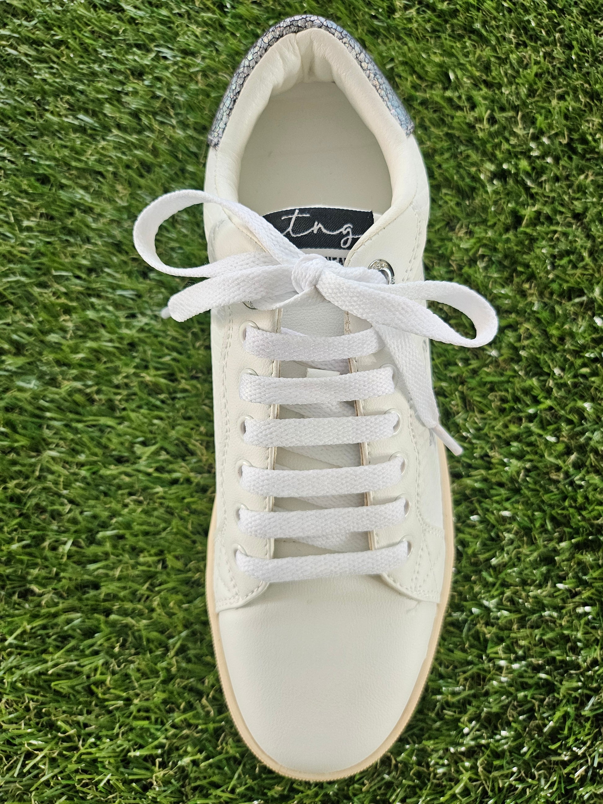 White sneaker with laces on a grass background