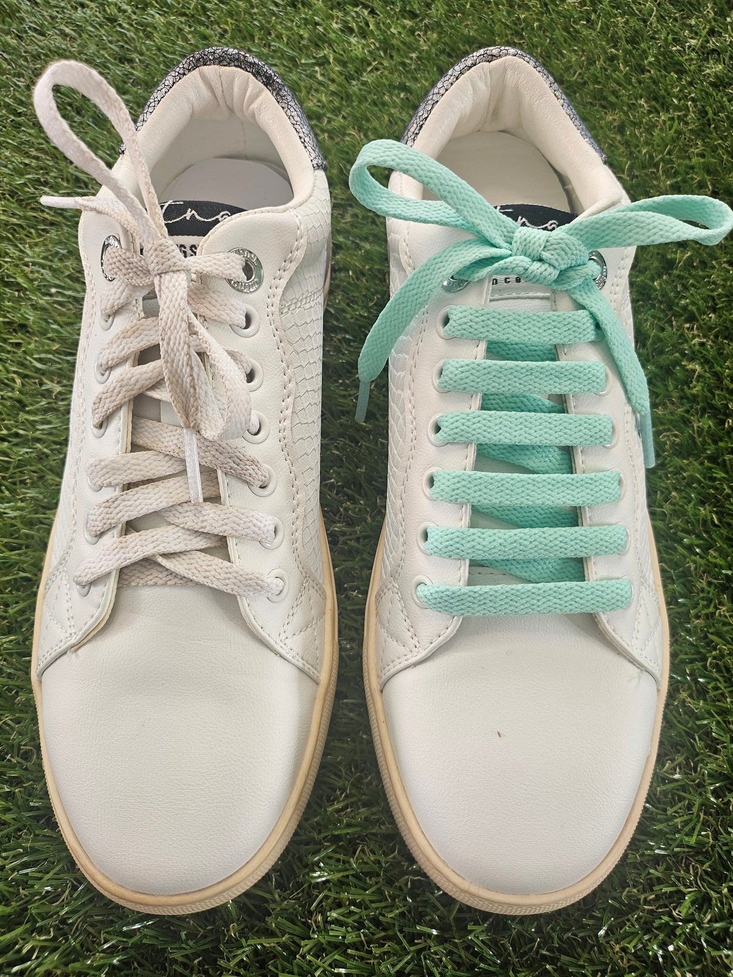 White sneakers with light green laces on a grass background