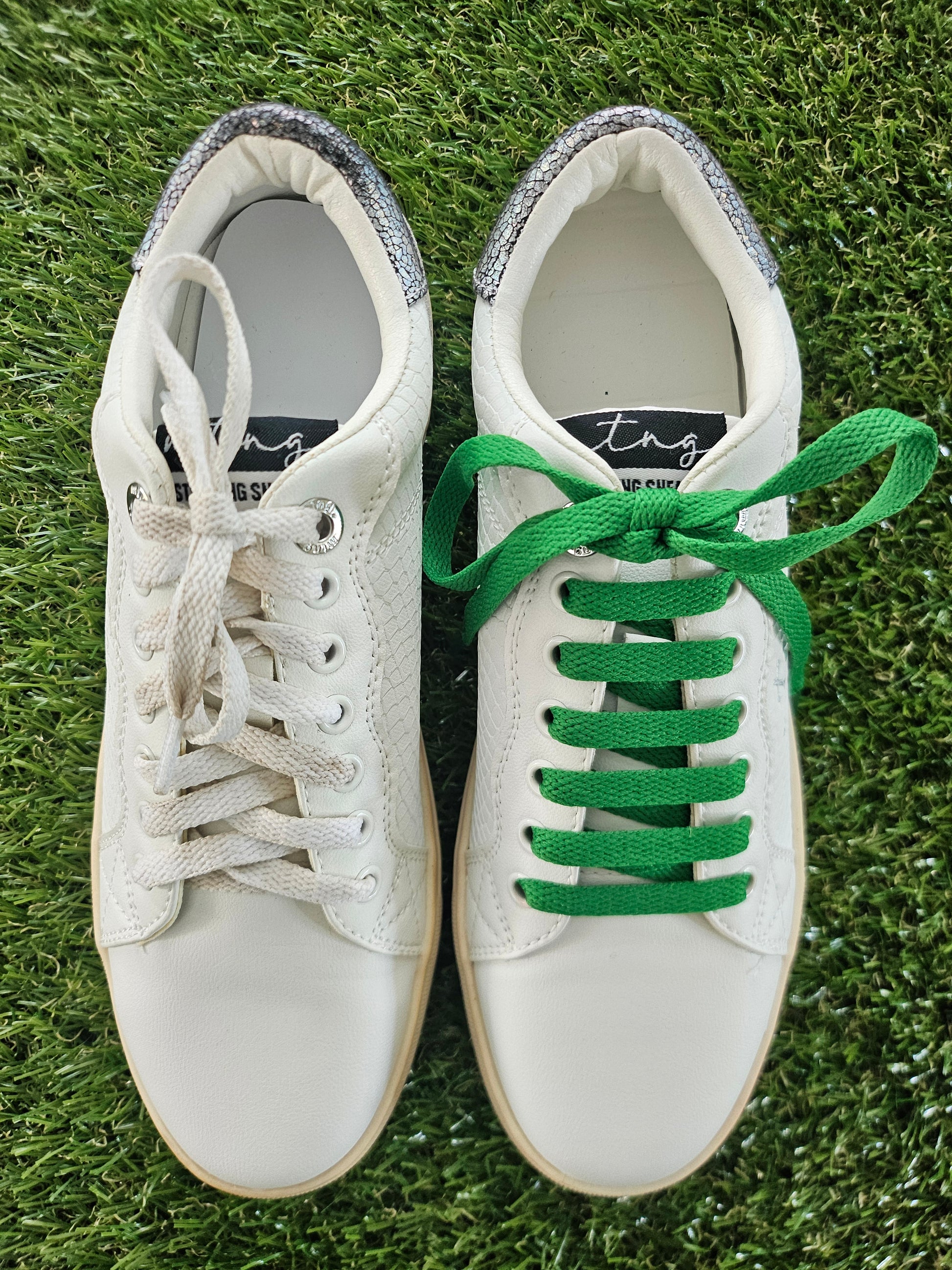 White sneakers with green laces on a grass background