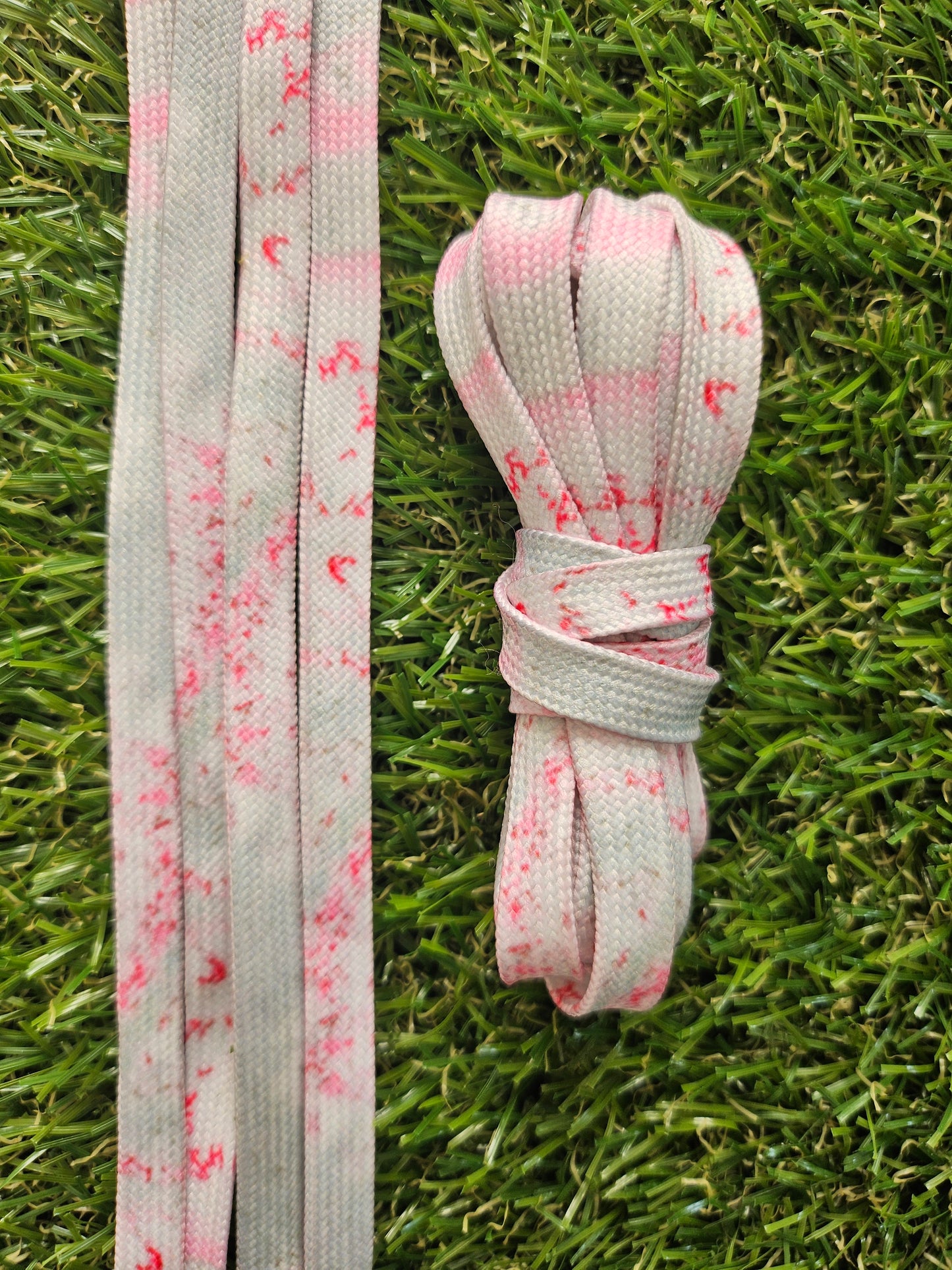 Gray shoelaces with pink speckles on grass