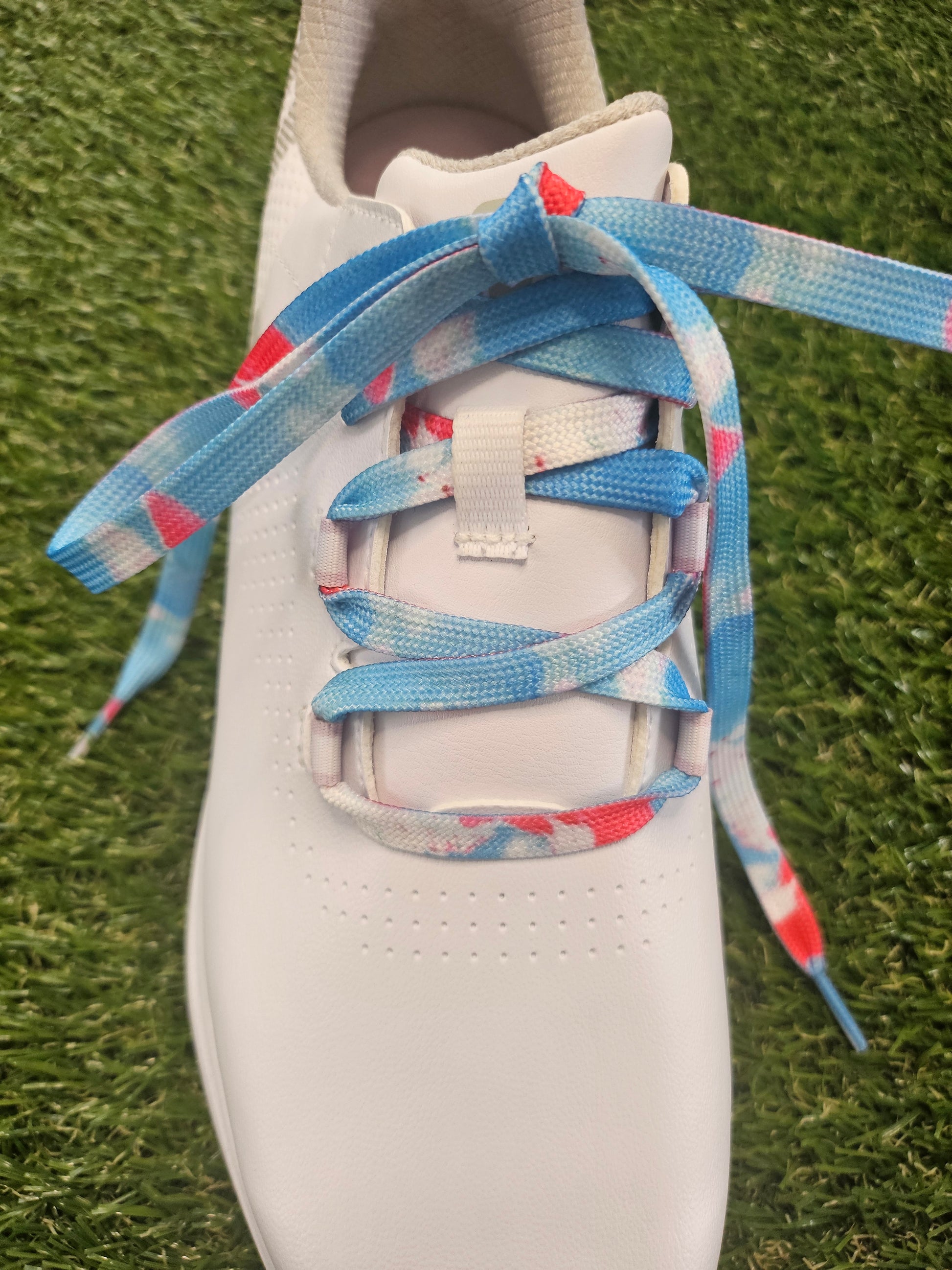 White golf shoe with colourful laces on a grass background