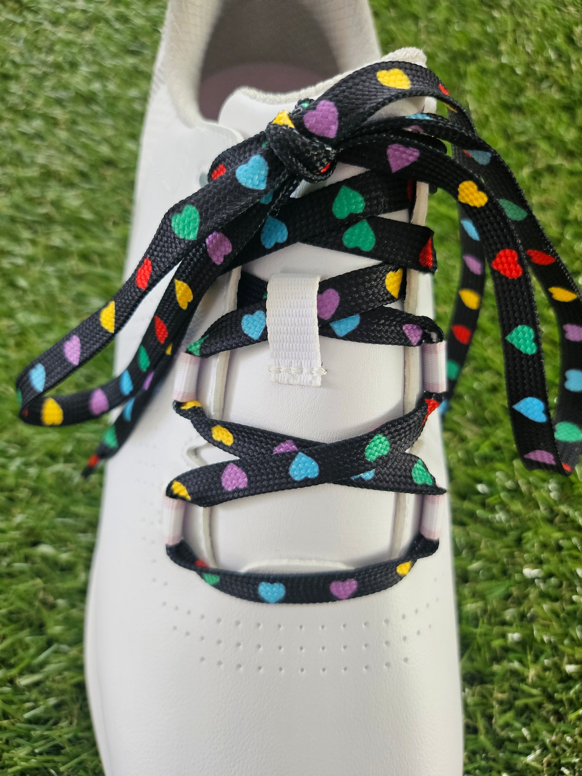 white ladies golf shoe with black laces with multi coloured heart pattern