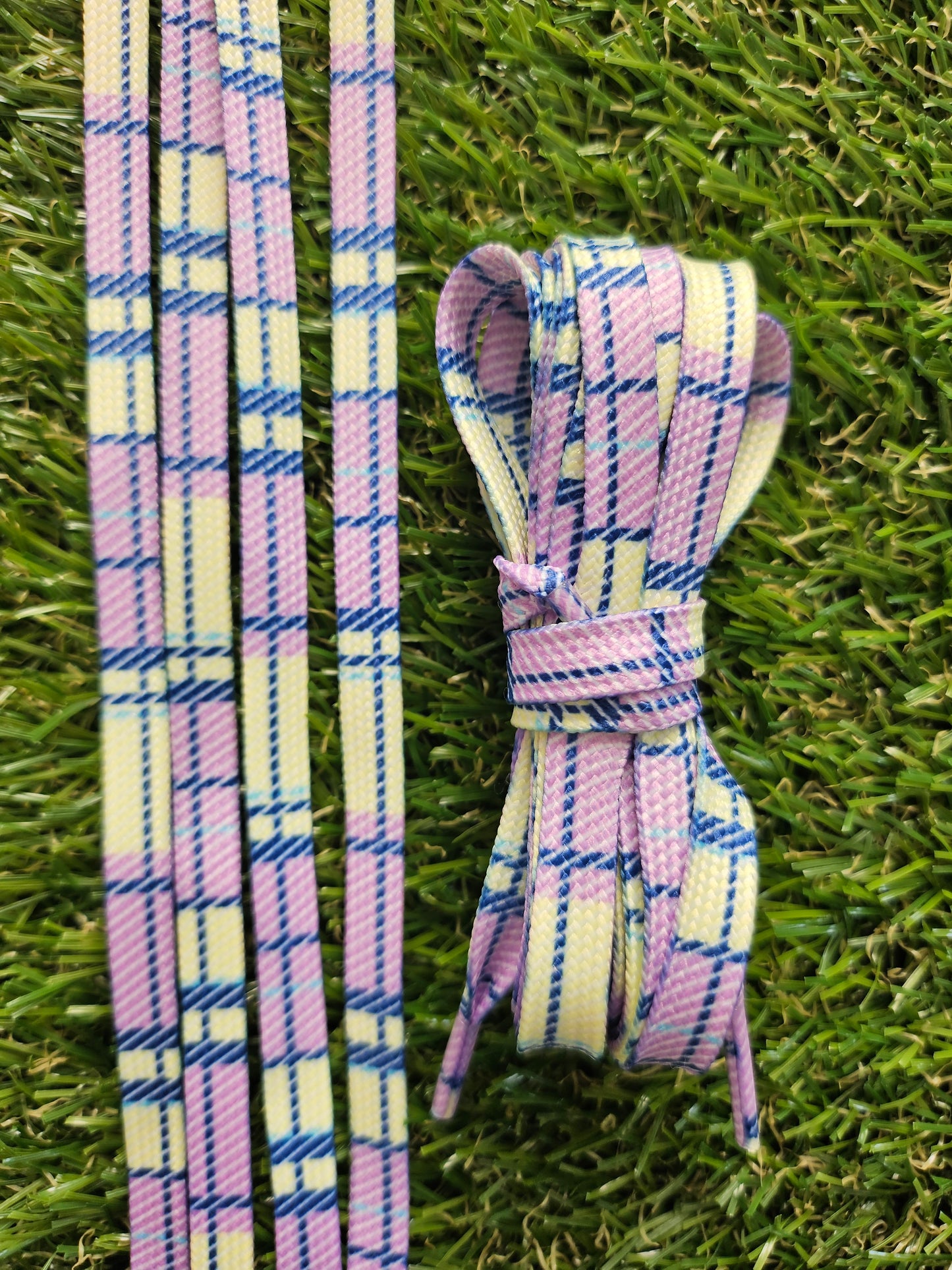 Yellow and purple shoelaces in lemon and lilac colours laid on grass