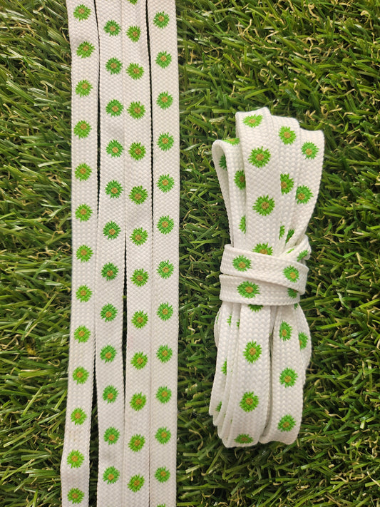 White shoelaces with green floral daisy patterns on grass