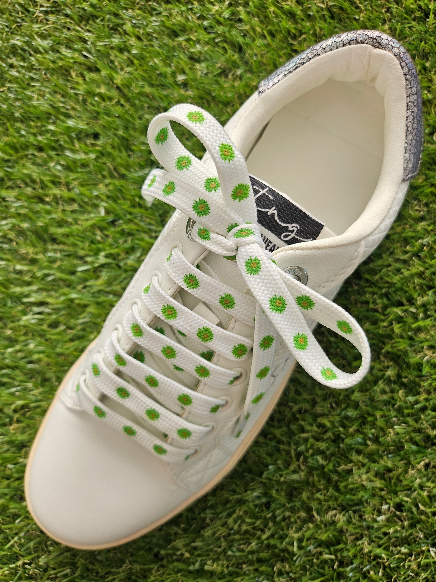 White sneaker with green flowers laces on grass