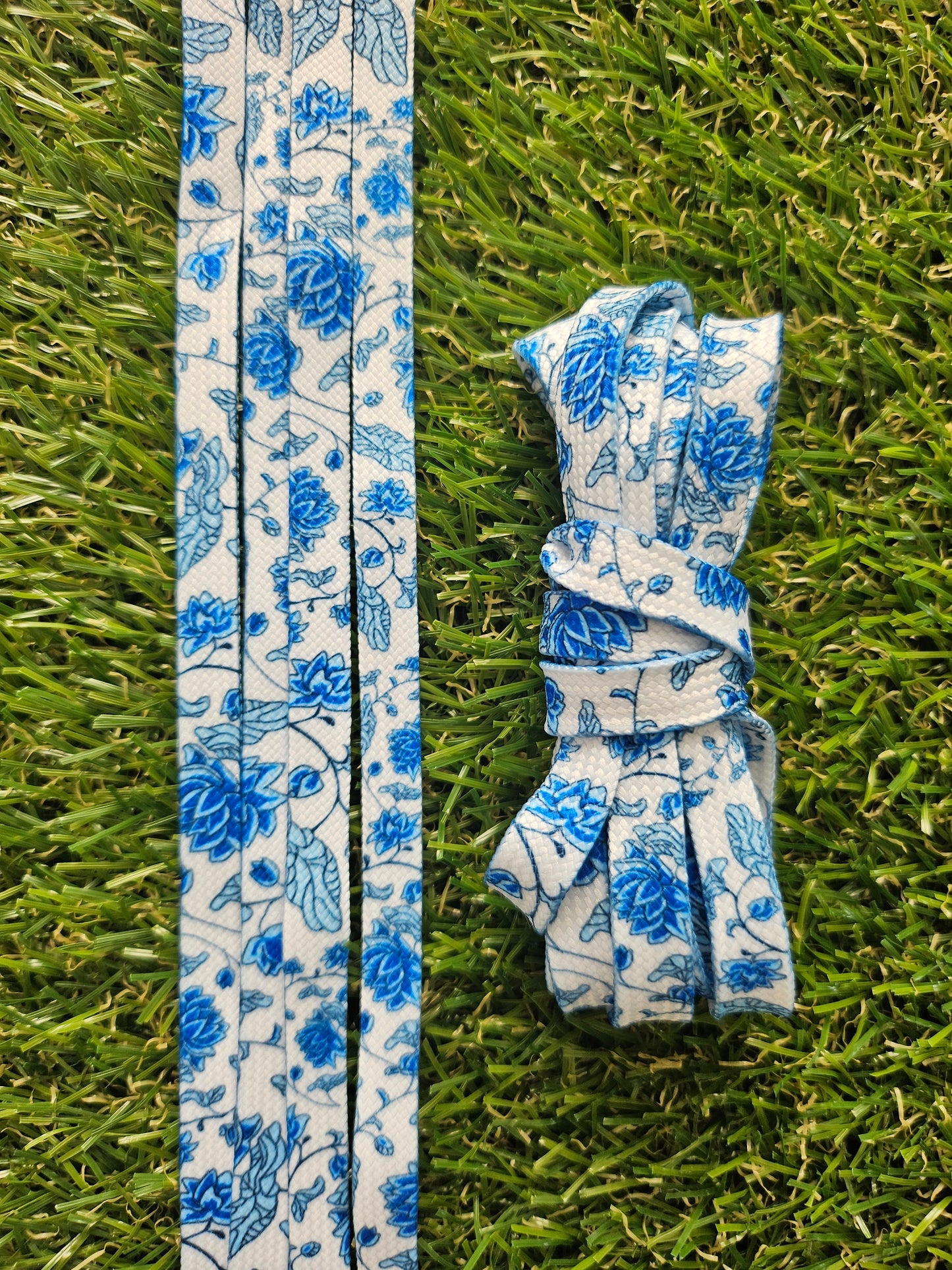Midnight Garden white shoelaces with blue floral pattern on grass background