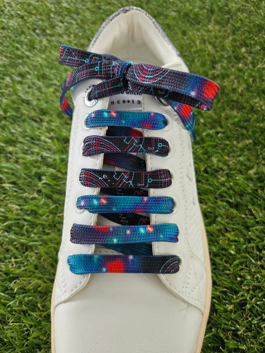 White sneaker with space patterned colorful laces on a grass background