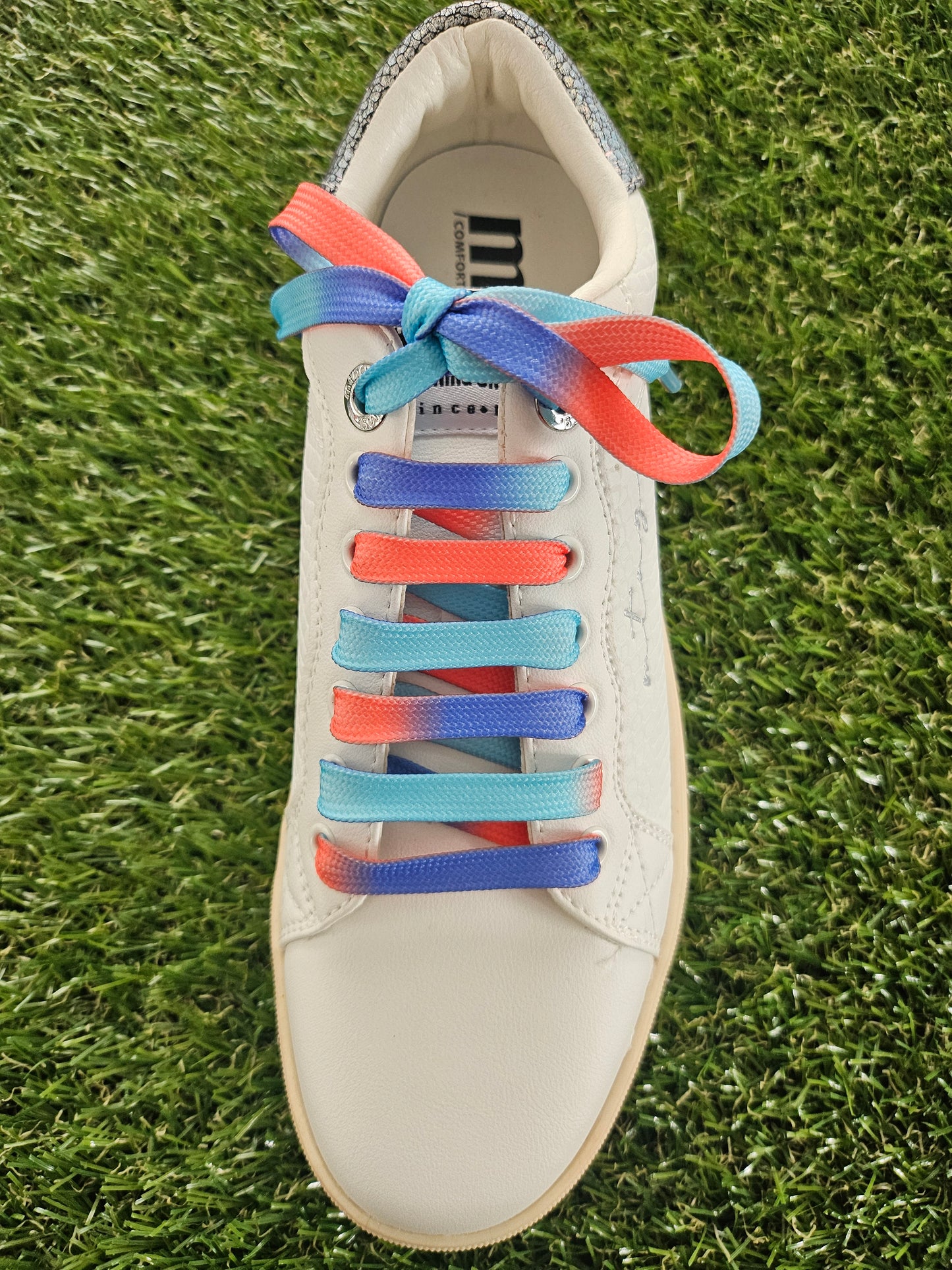 ocean sunset coloured shoelaces in a white trainer on grass background