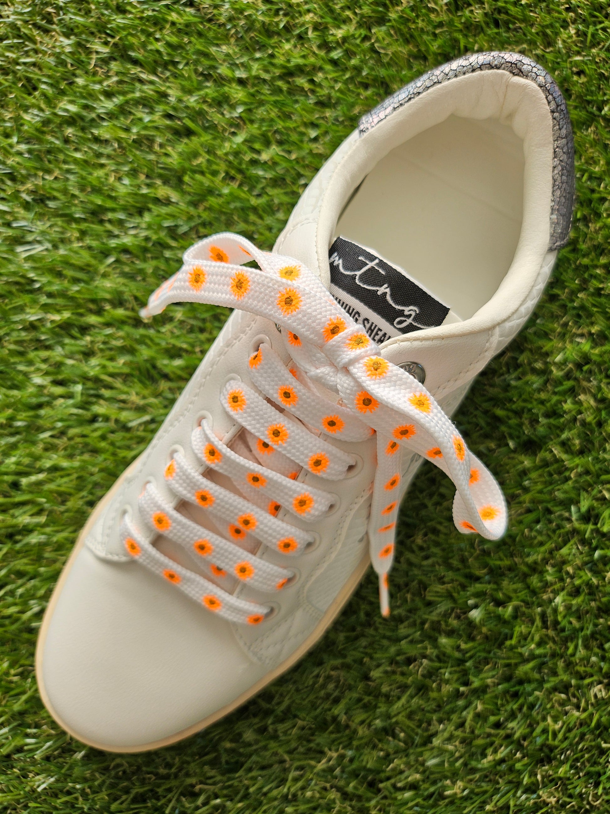 White trainer with orange flowers on a grass background