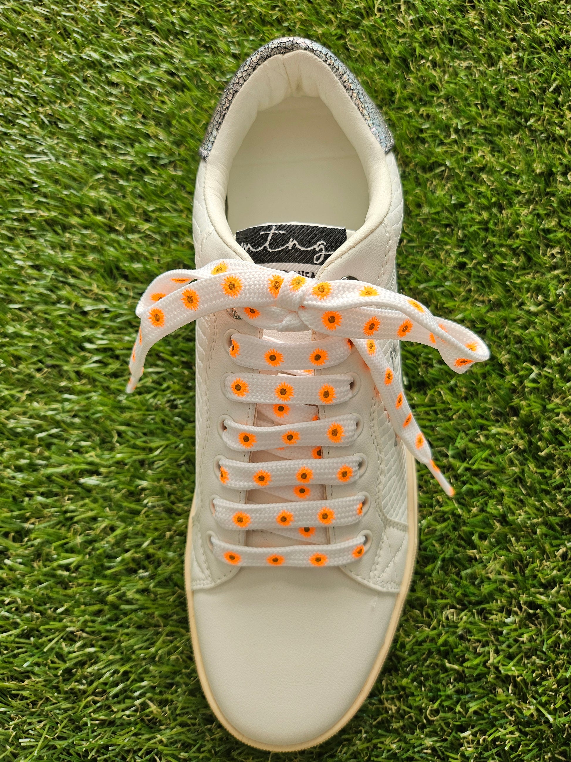 White sneaker with orange accents on a grass background