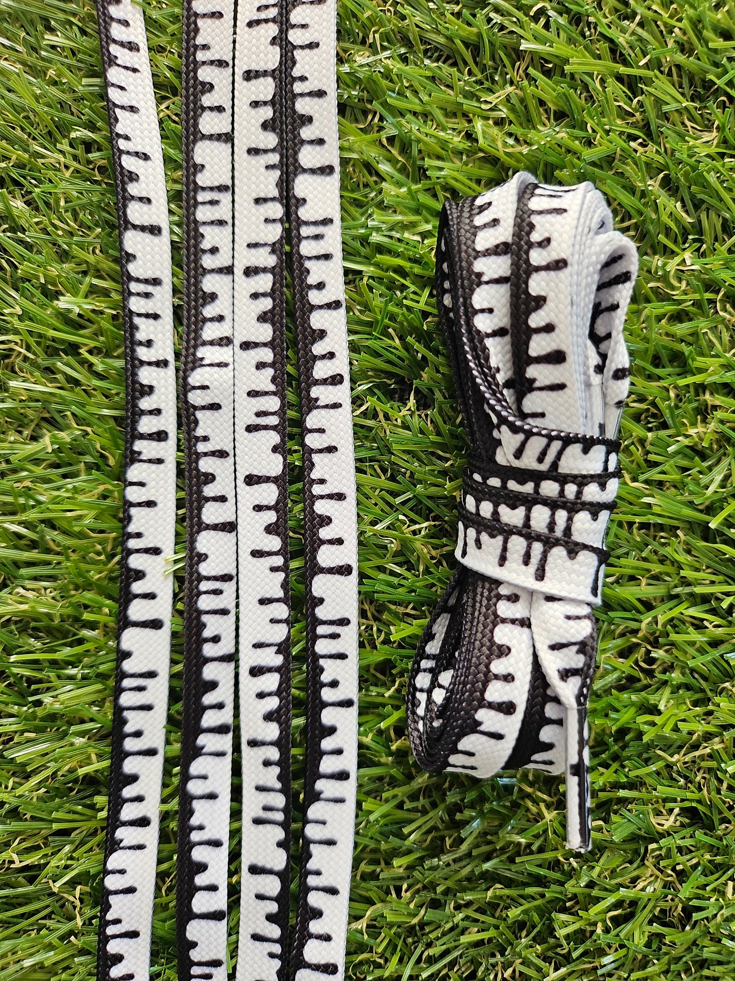 White laces with black paint drip effect on green grass