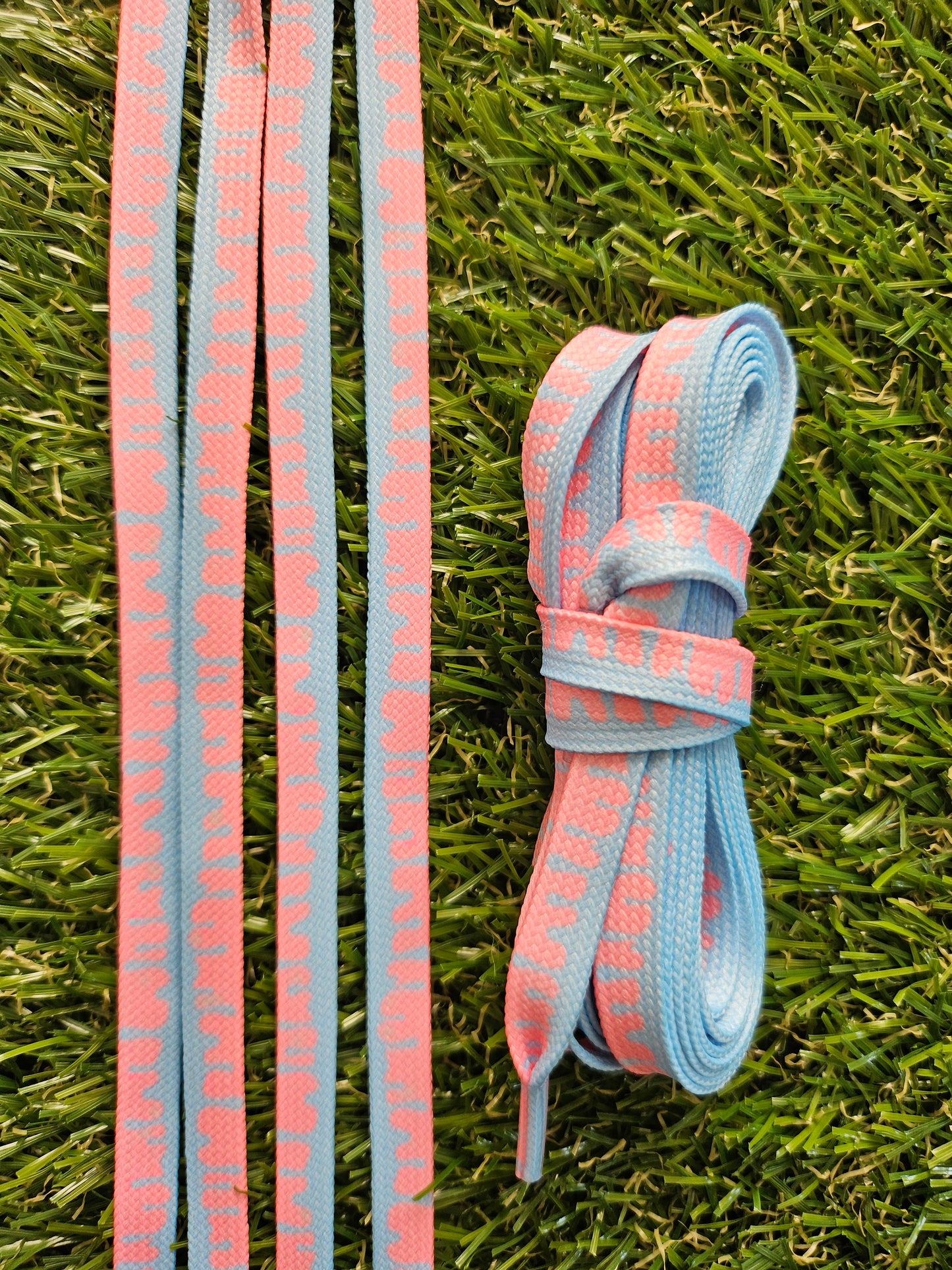 Paint Drip ShoeLaces - White & Coral Pink lying on grass