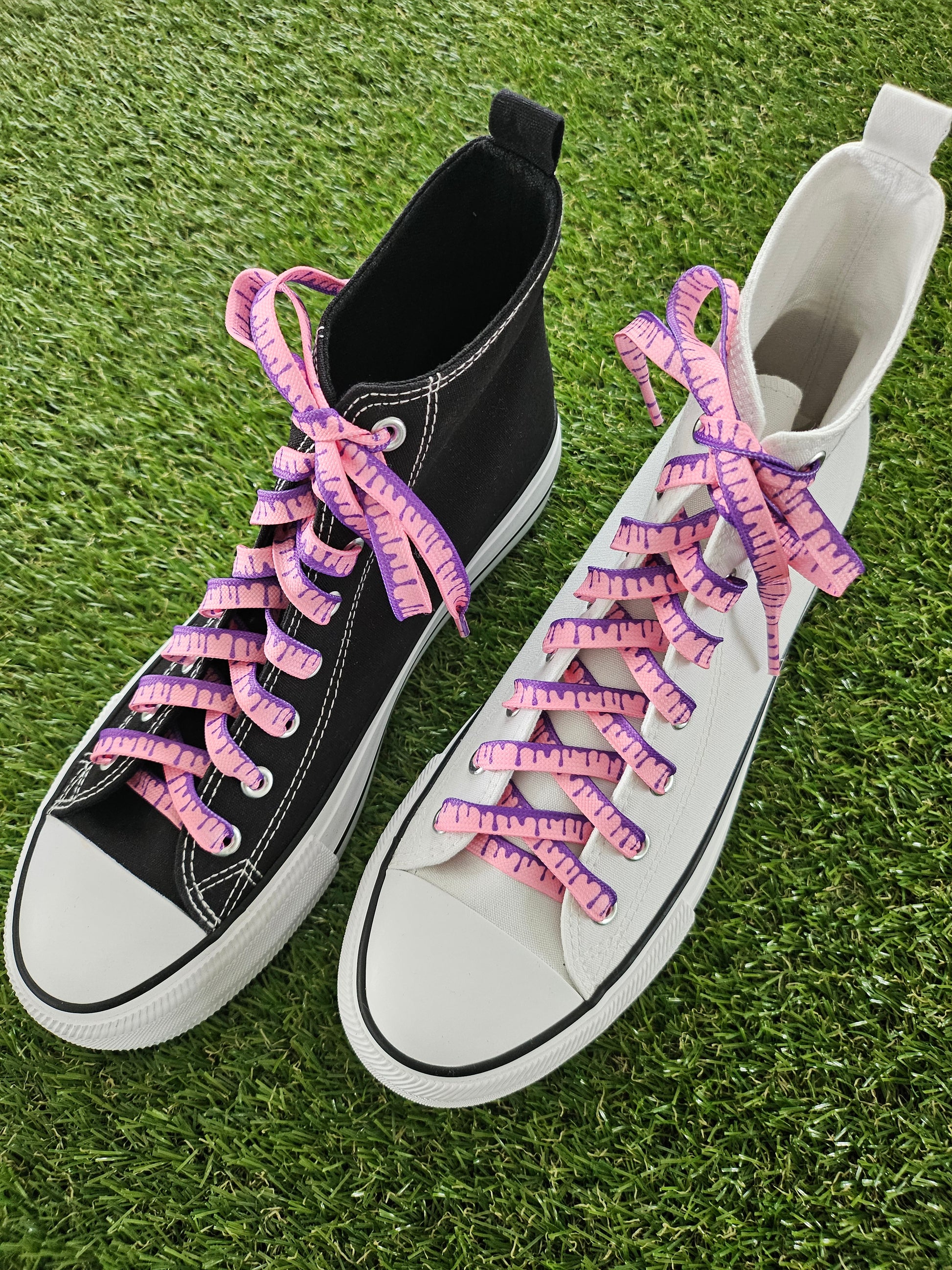 Black and white sneakers with pink shoelaces on grass