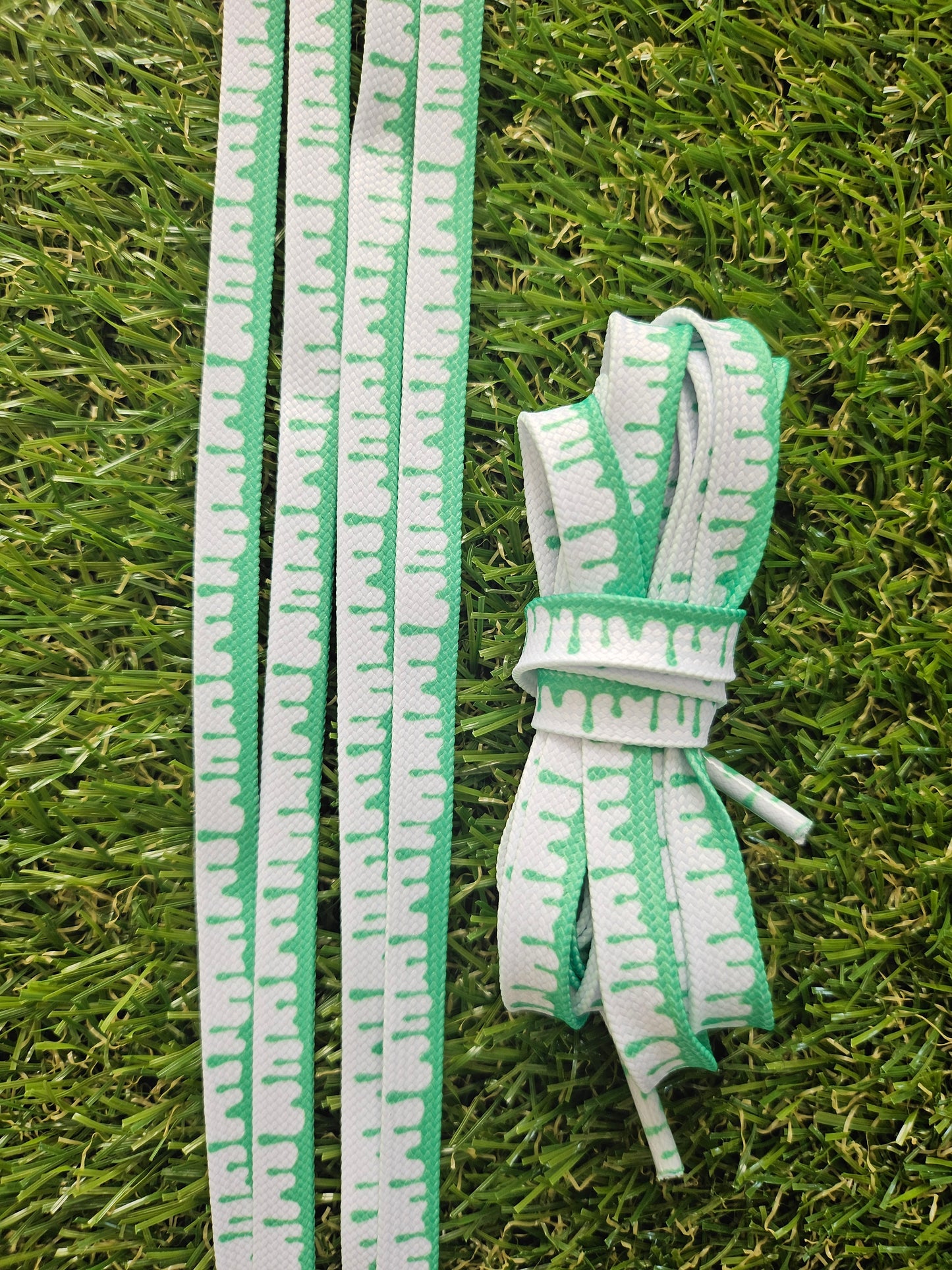 Green and white shoelaces on grass