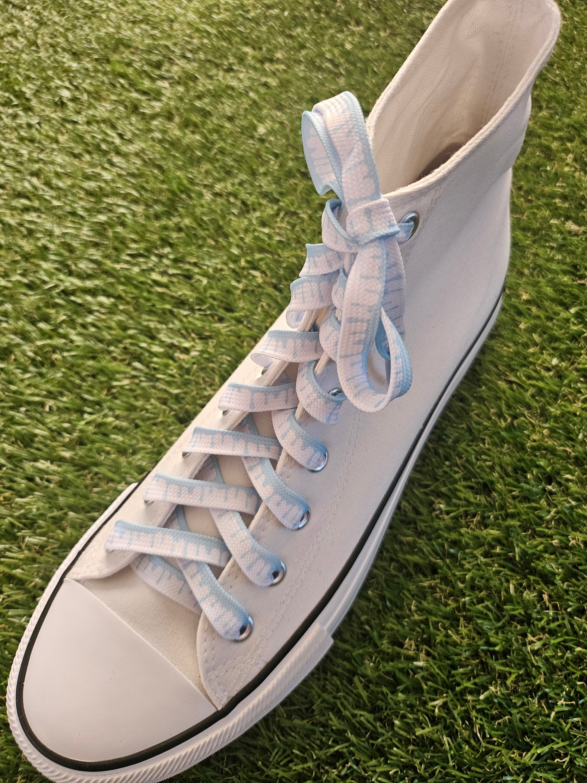 White sneaker with blue laces on a grass background