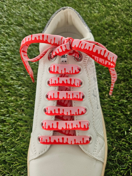 White sneaker with red laces on a grass background