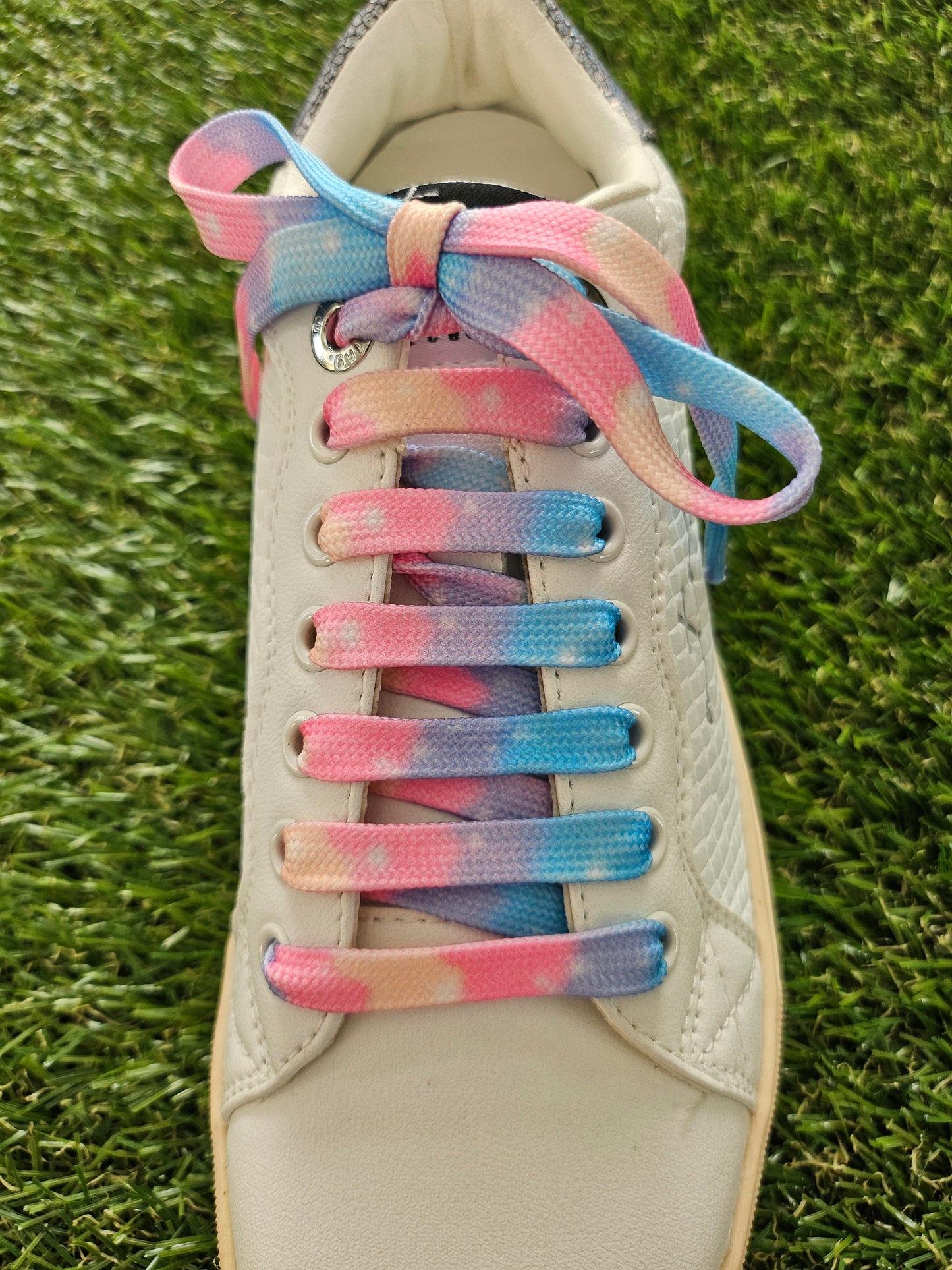 Shoe with colorful, gradient shoelaces on a grass background