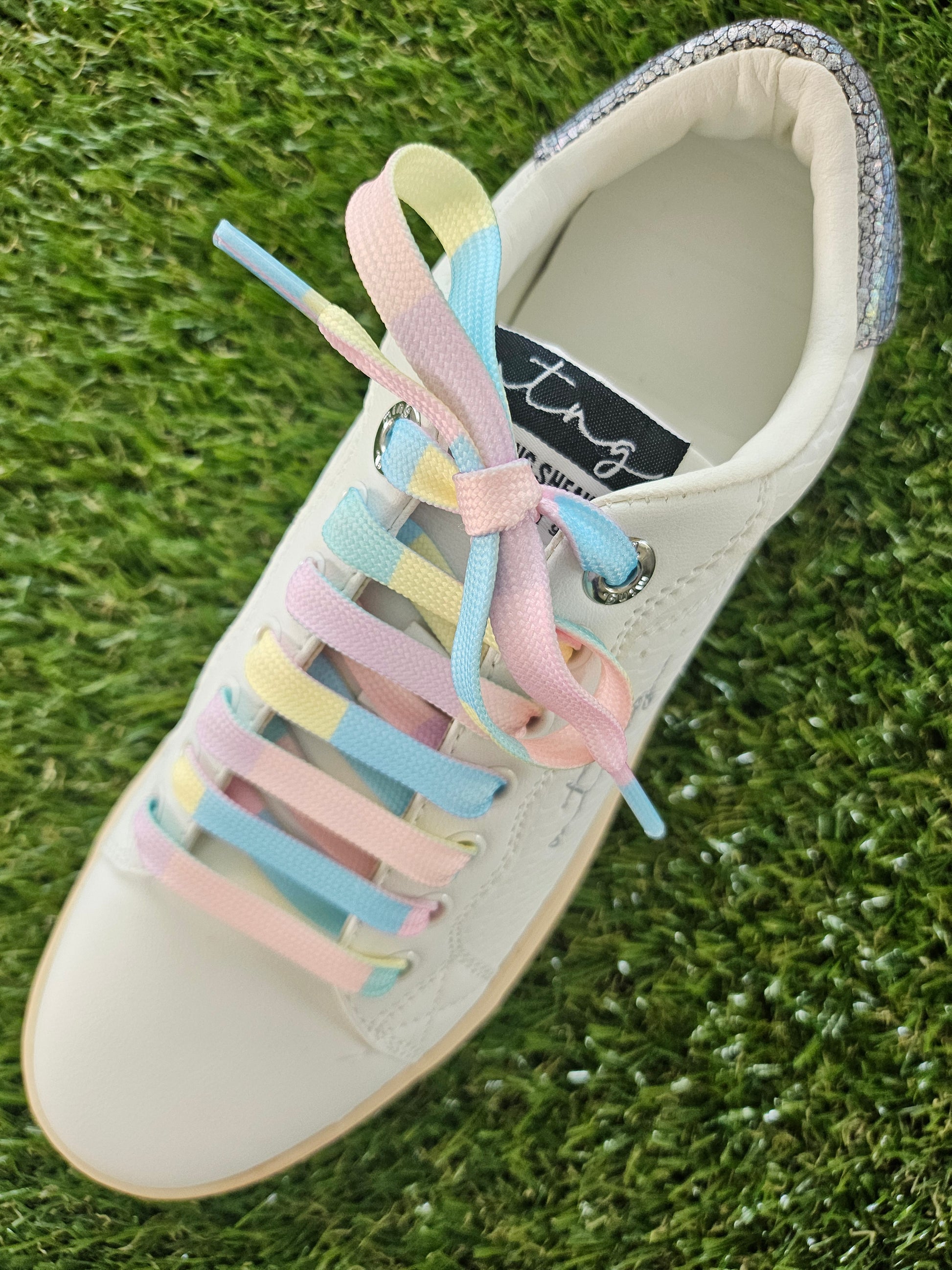 White sandal with colorful laces on a grass background
