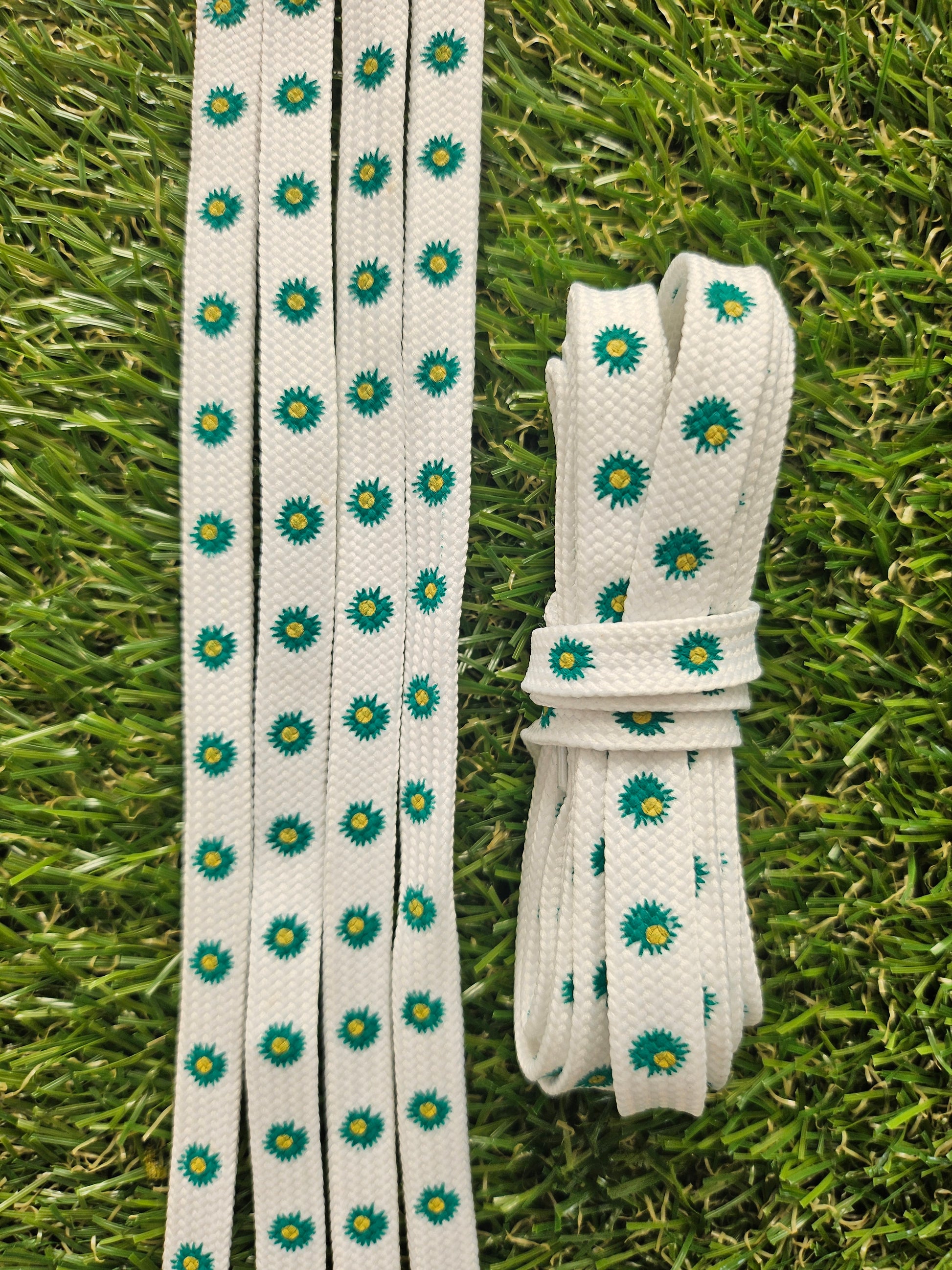 White shoelaces with pine green floral pattern on grass