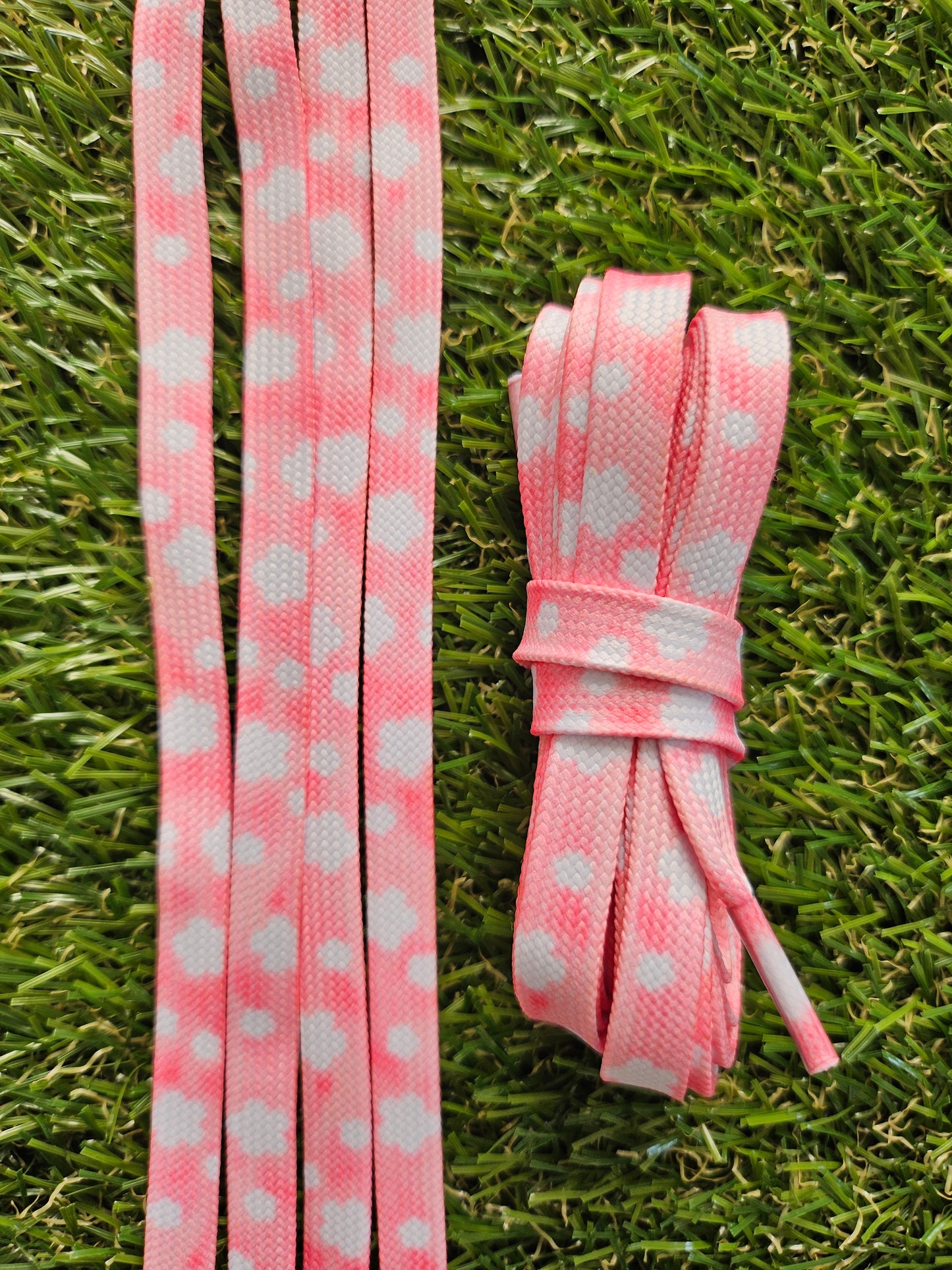 Pink laces with white flowers that look like clouds lying on grass