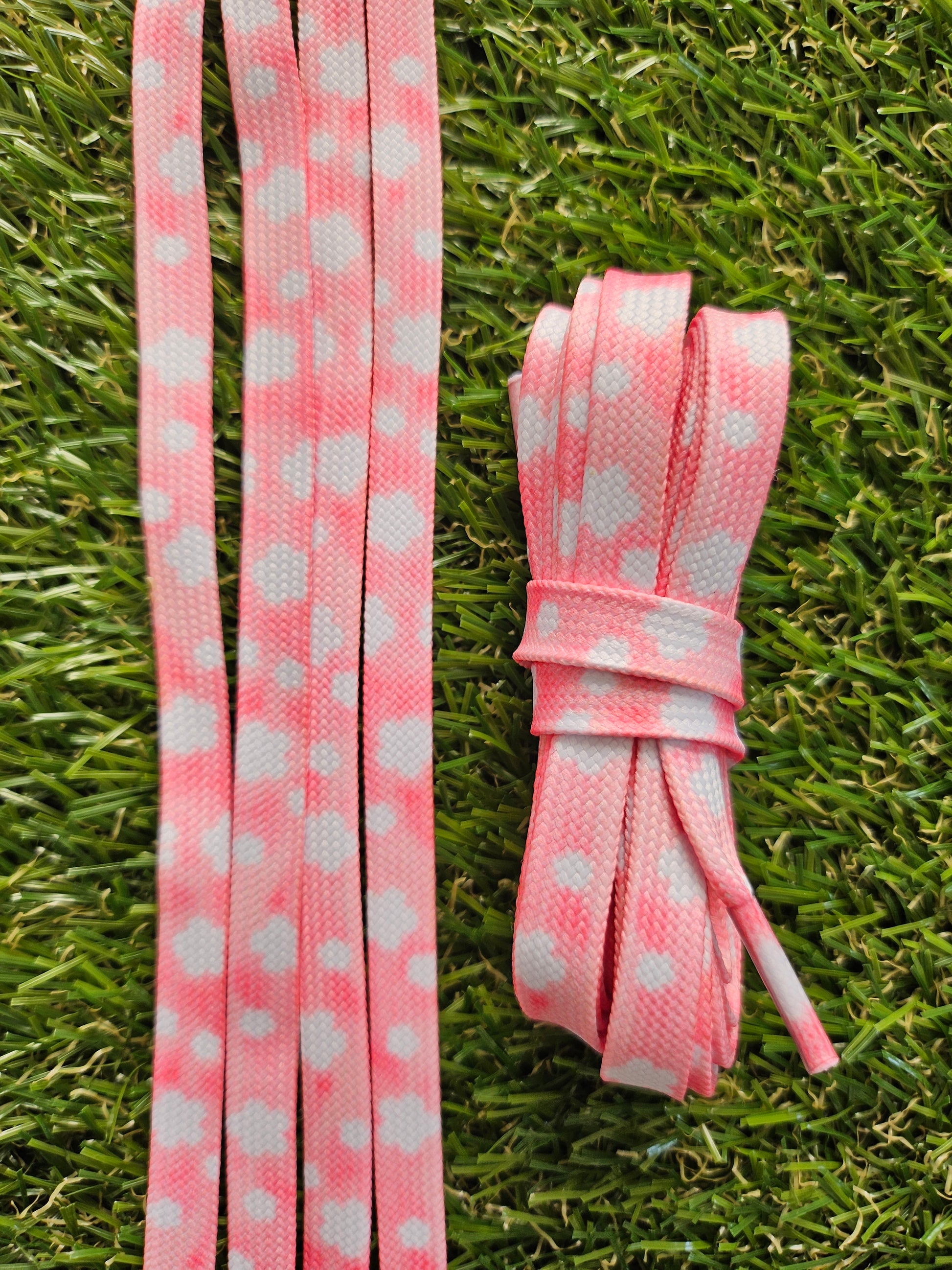 Pink laces with white flowers that look like clouds lying on grass