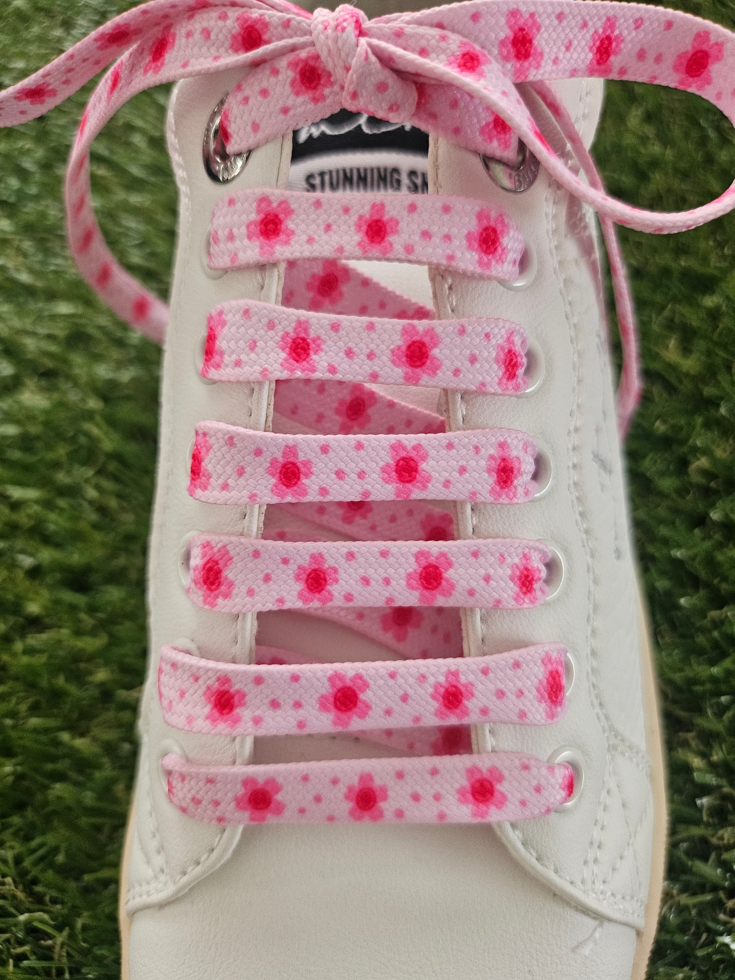 White sneaker with pink floral lace on grass