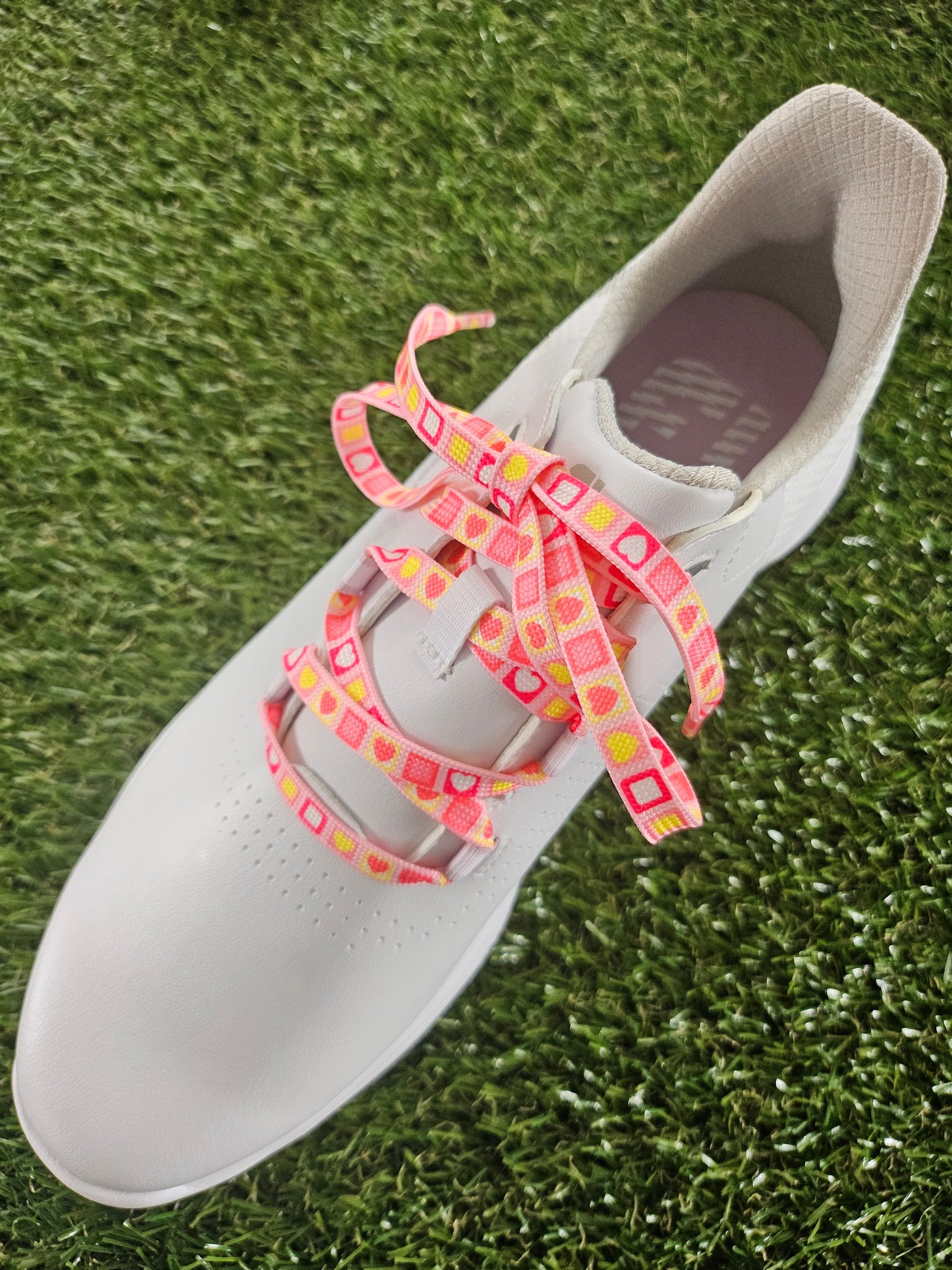 Pink Heart Candy Square Laces in a white ladies golf shoe on green grass
