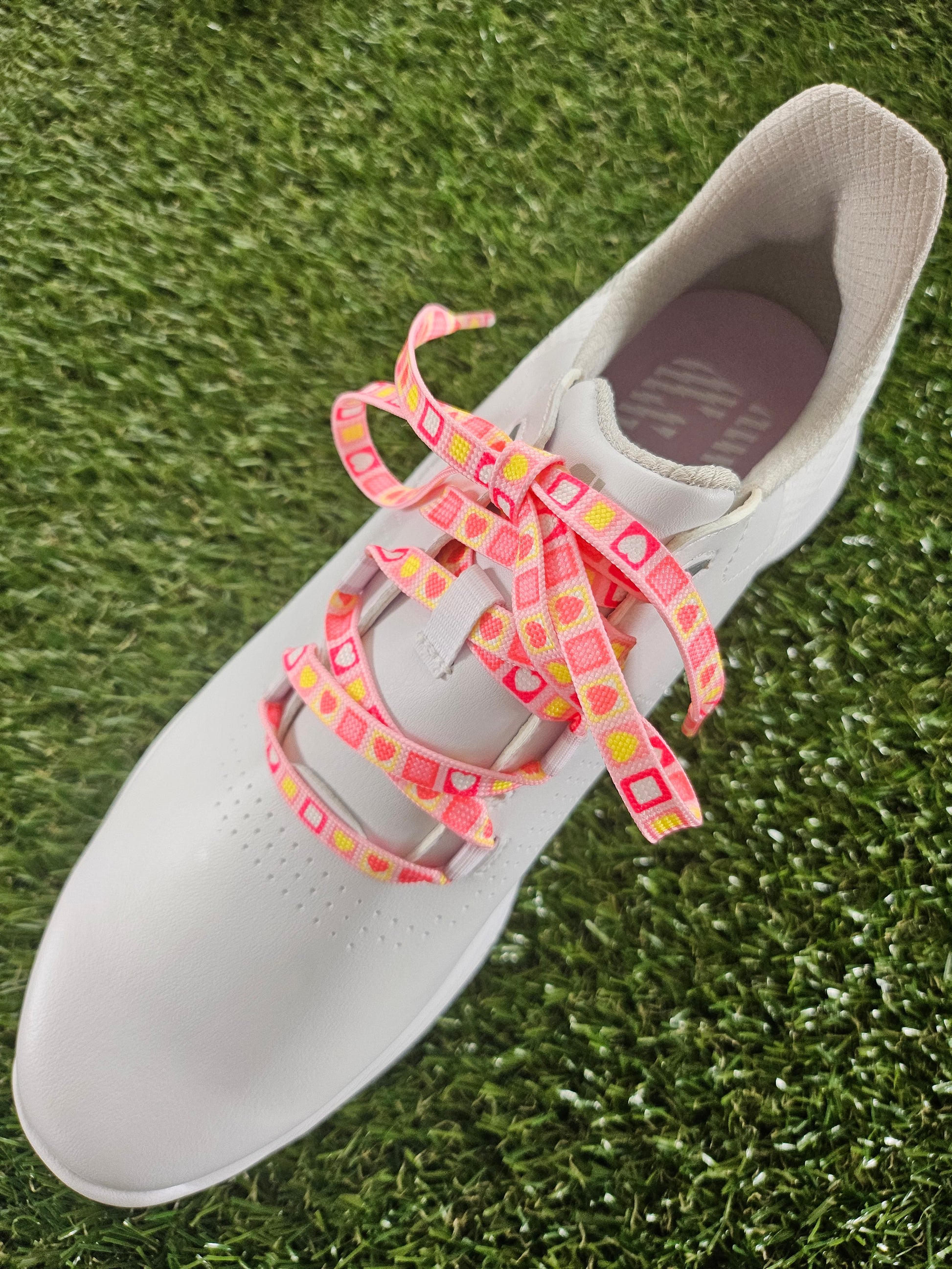 Pink Heart Candy Square Laces in a white ladies golf shoe on green grass
