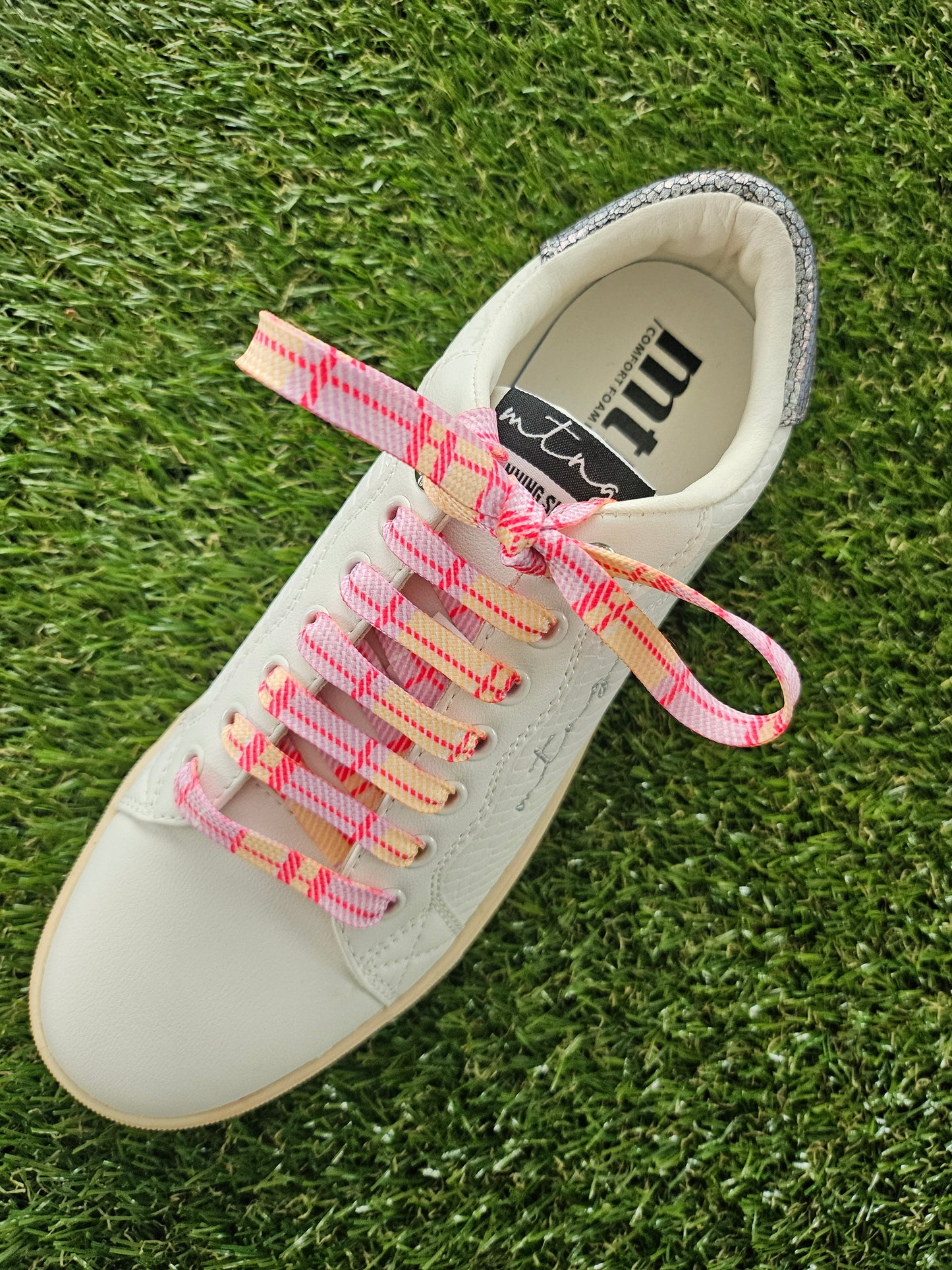 White sneaker with colourful scottish tartan shoelaces on grass