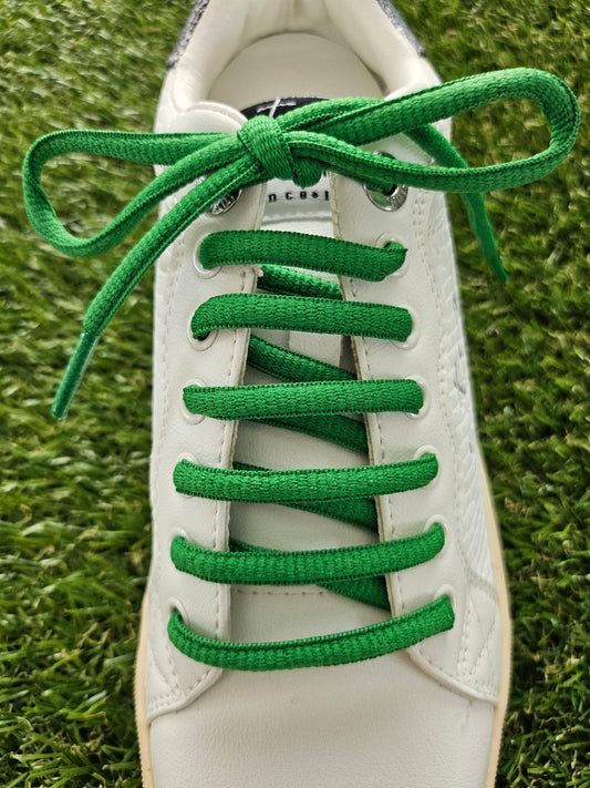 green shoelaces on white trainer on grass