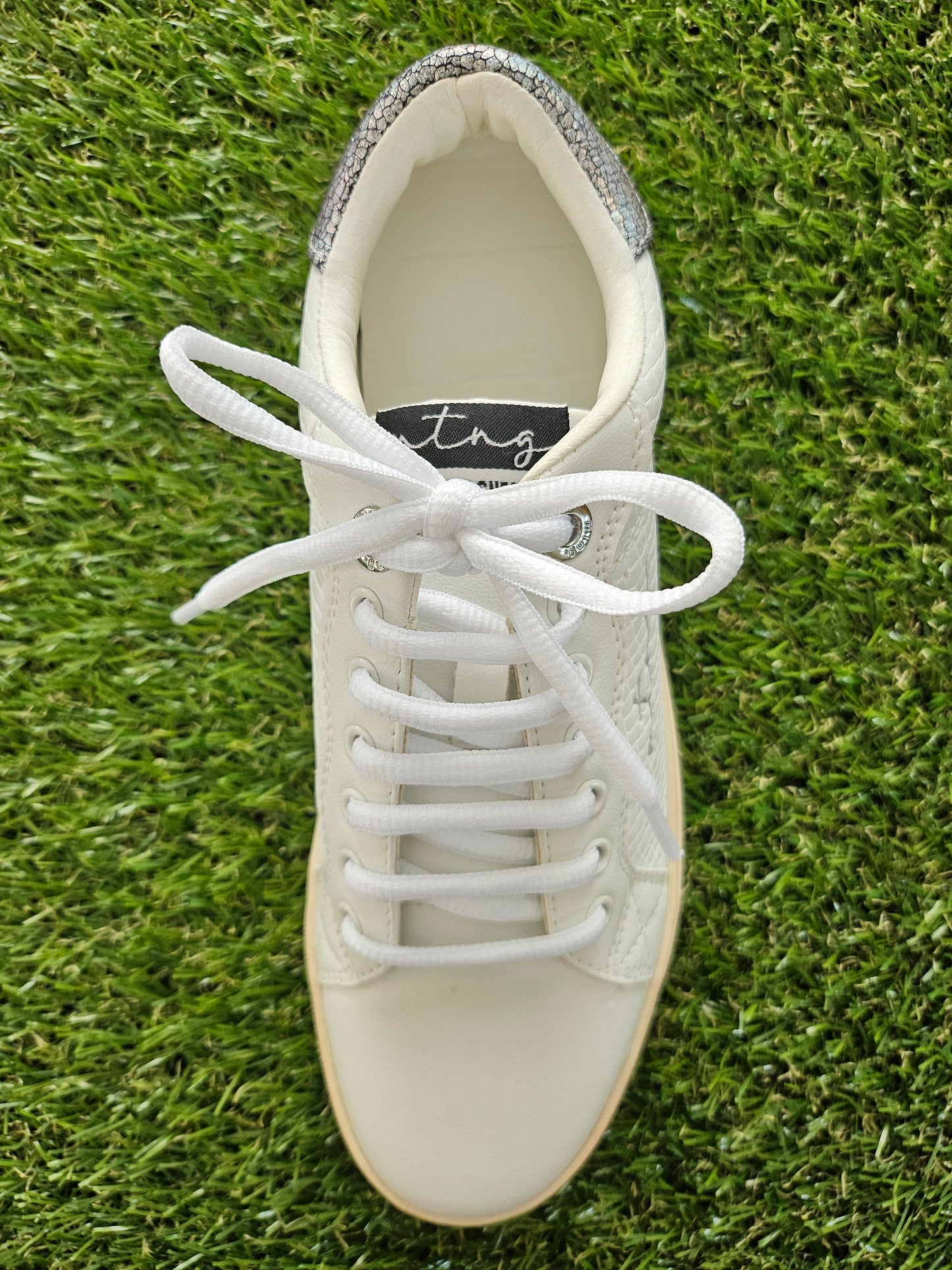 White sneaker with laces on a grass background