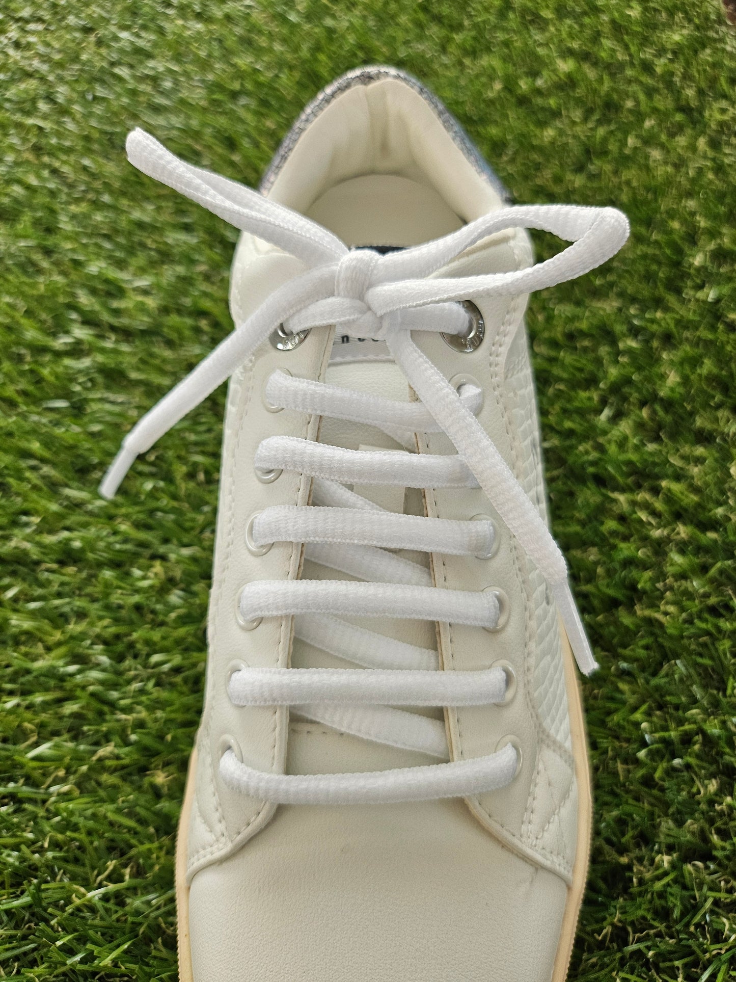 White sneaker with laces on a grass background